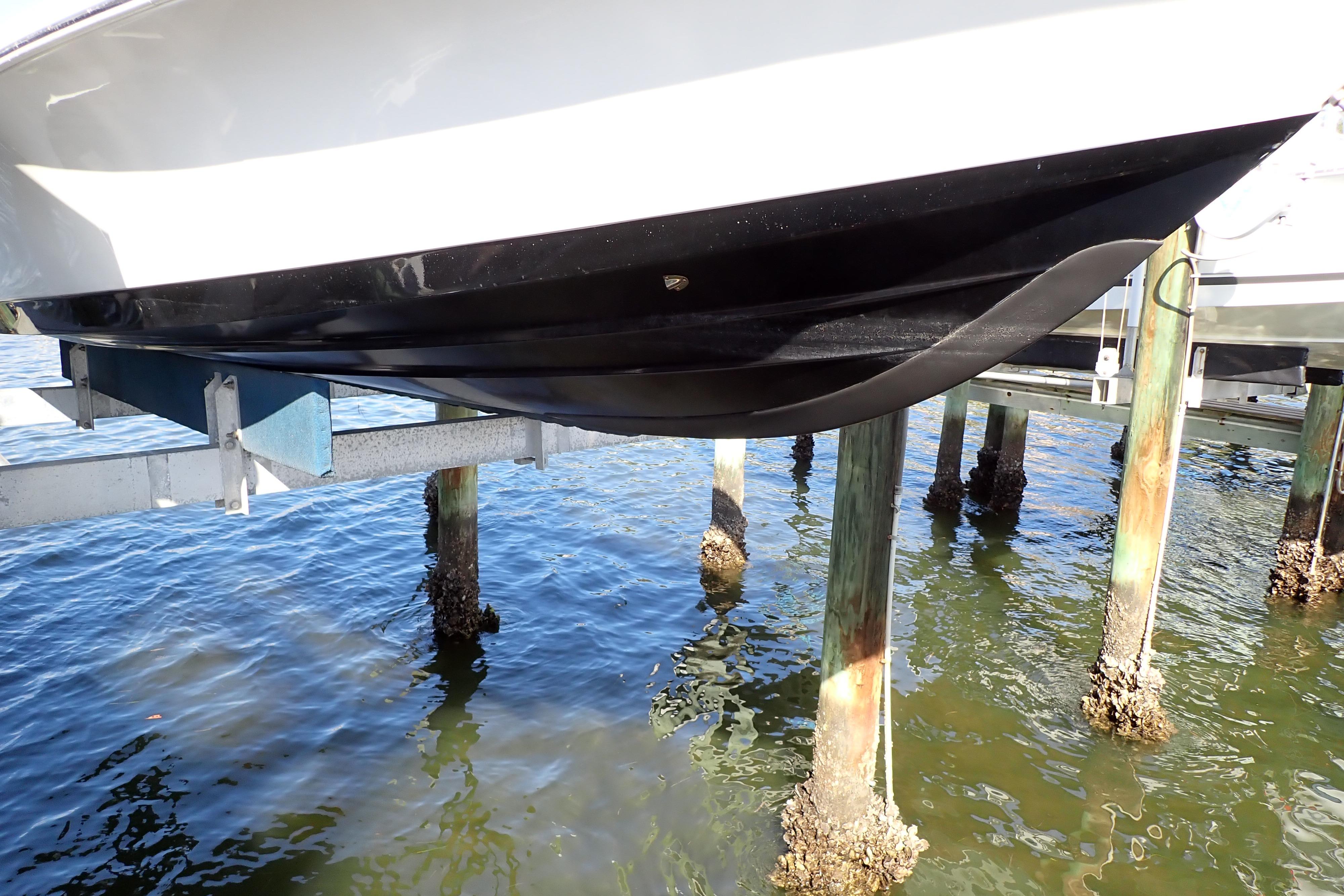 2015 Blue Wave 2400 PureBay boat hull on lift above water.