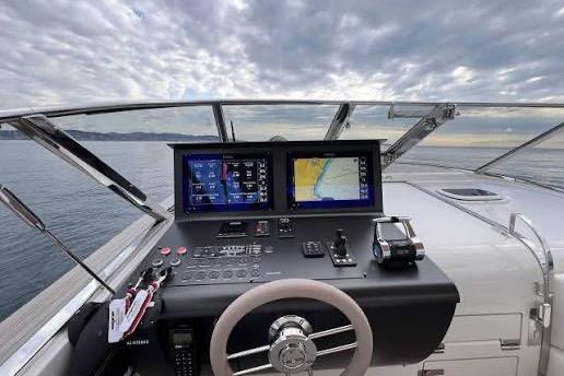 Cockpit view of 2023 Itama 45RS yacht with navigation screens and steering wheel.