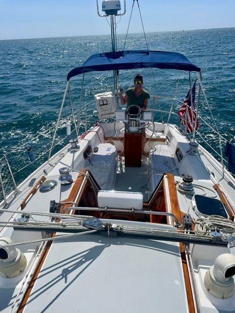 A 1989 Catalina 34 sailing on open water with a person at the helm.