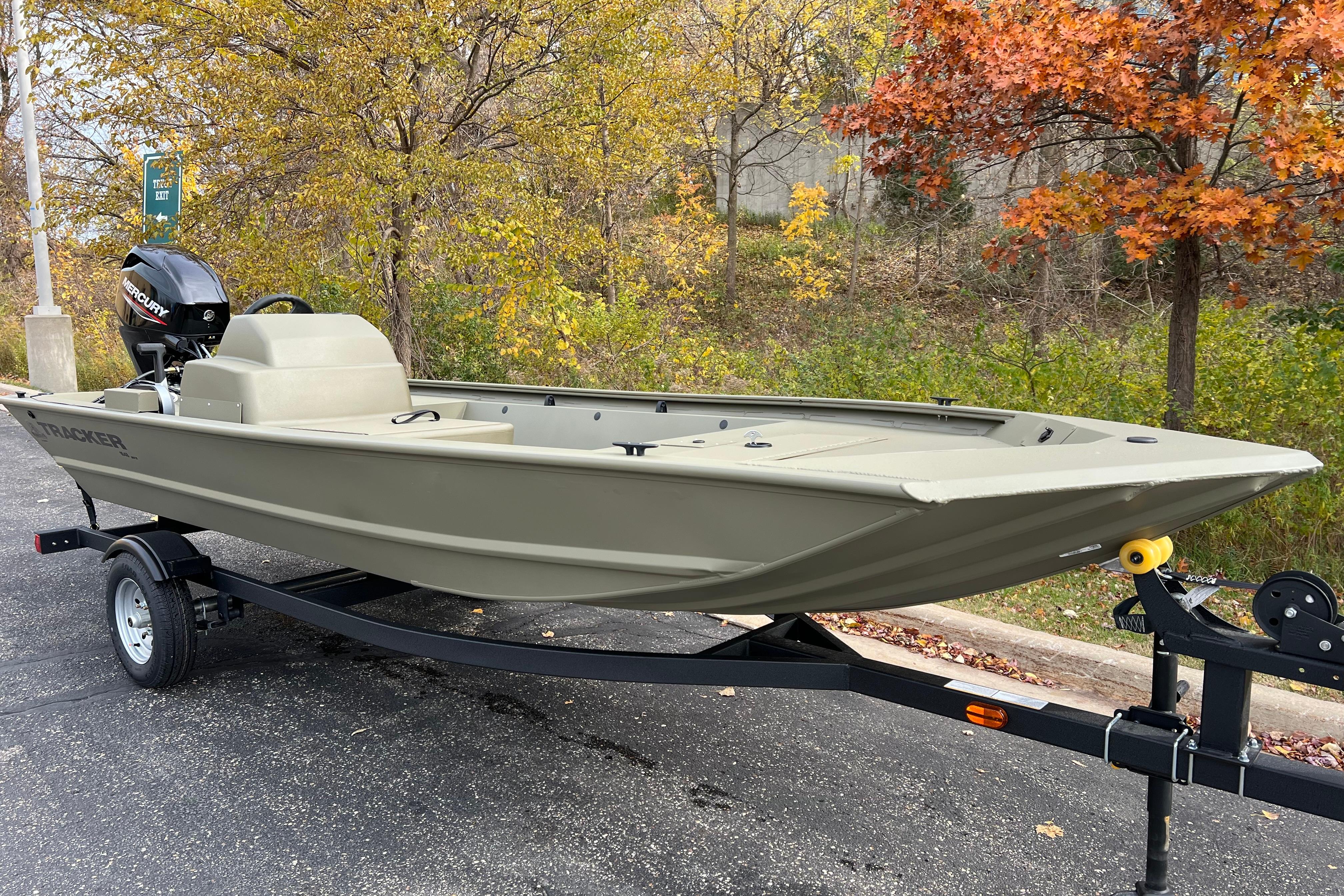 2026 Tracker Grizzly 1648 SC boat on trailer, parked near autumn trees.