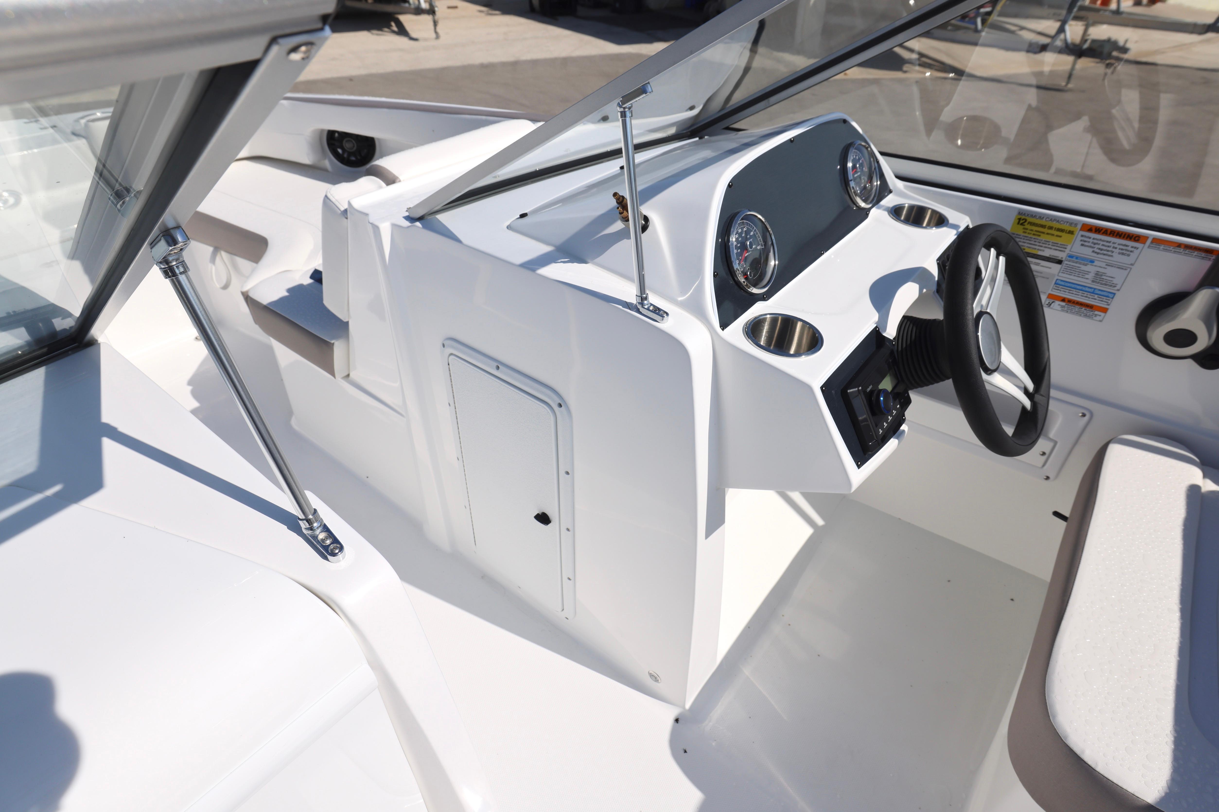 2026 Hurricane SunDeck 235 OB boat cockpit with steering wheel and dashboard controls.