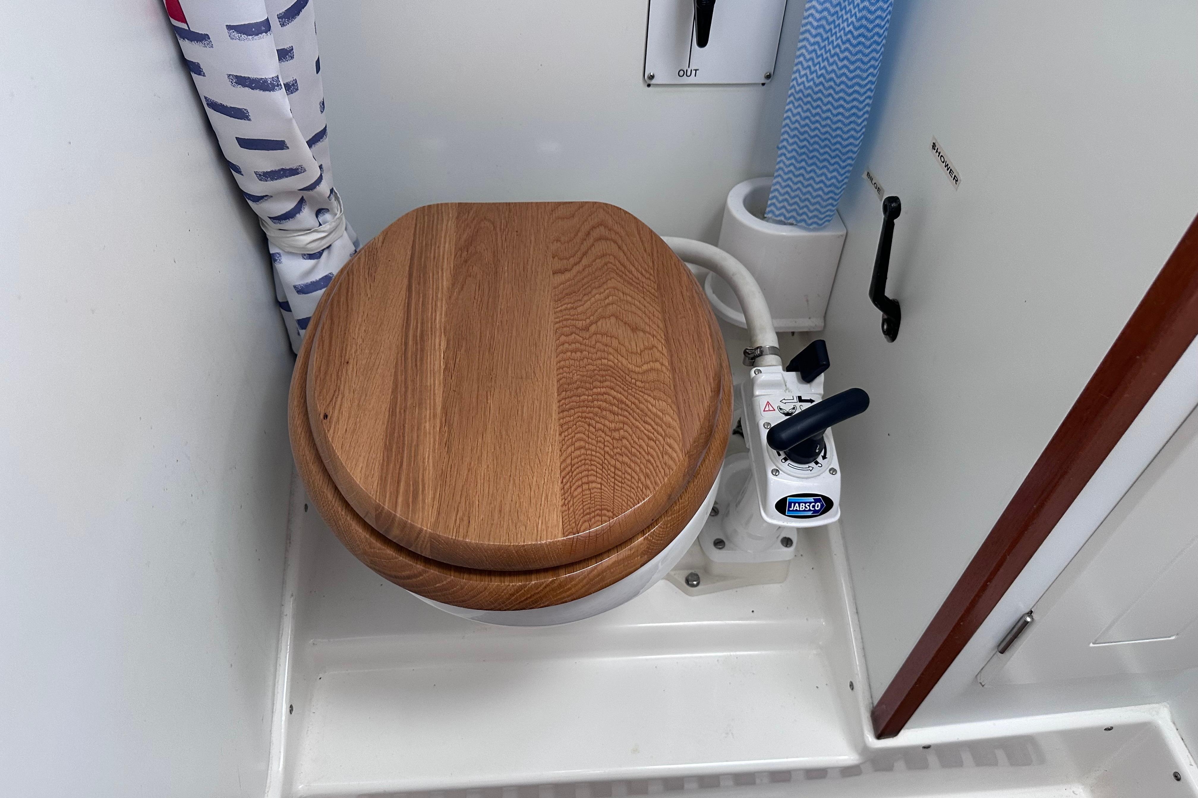 Wooden toilet seat in 1999 Hallberg-Rassy 39 yacht bathroom with Jabsco pump.