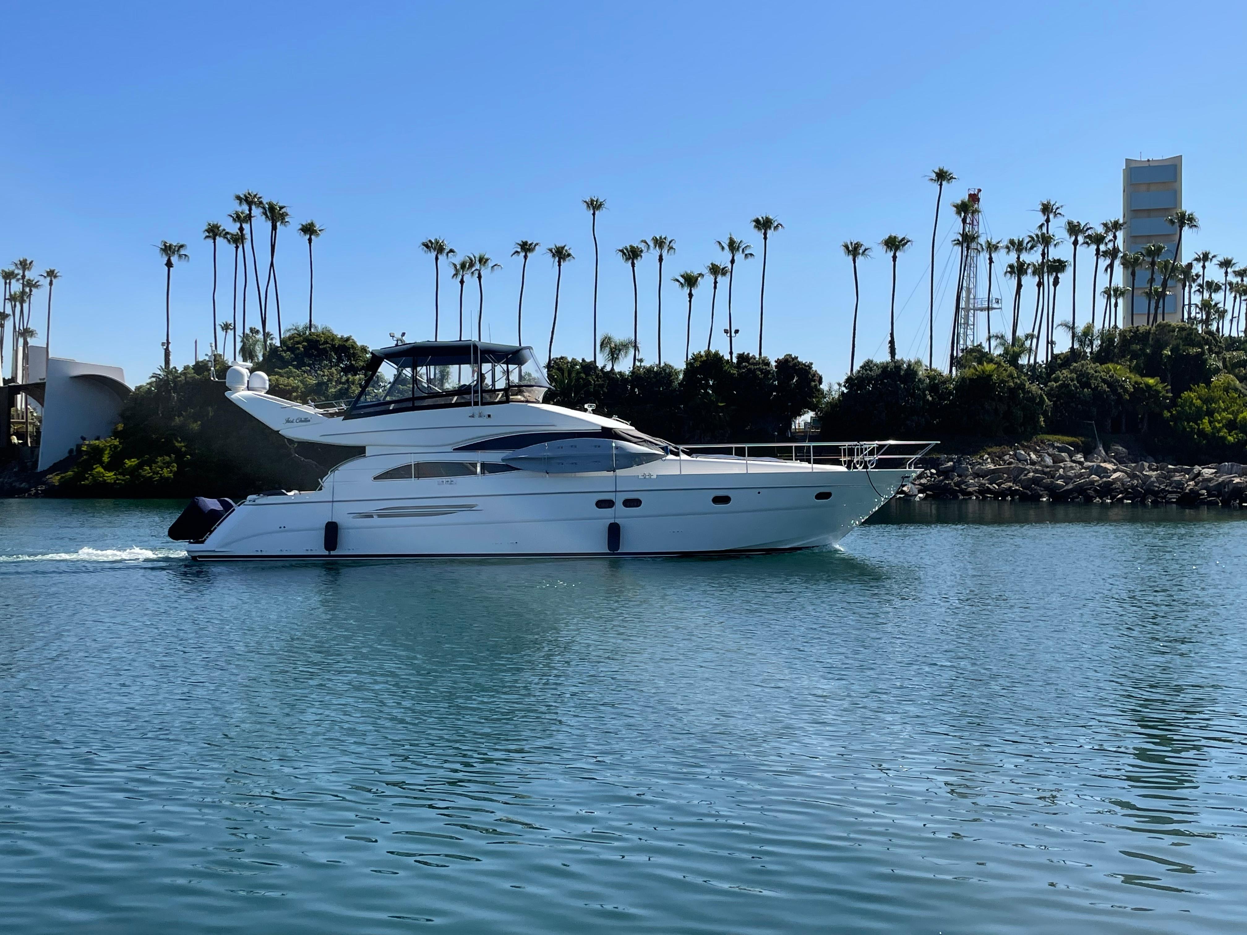2006 Viking Princess 61 Flybridge yacht cruising on calm water with palm trees in the background.