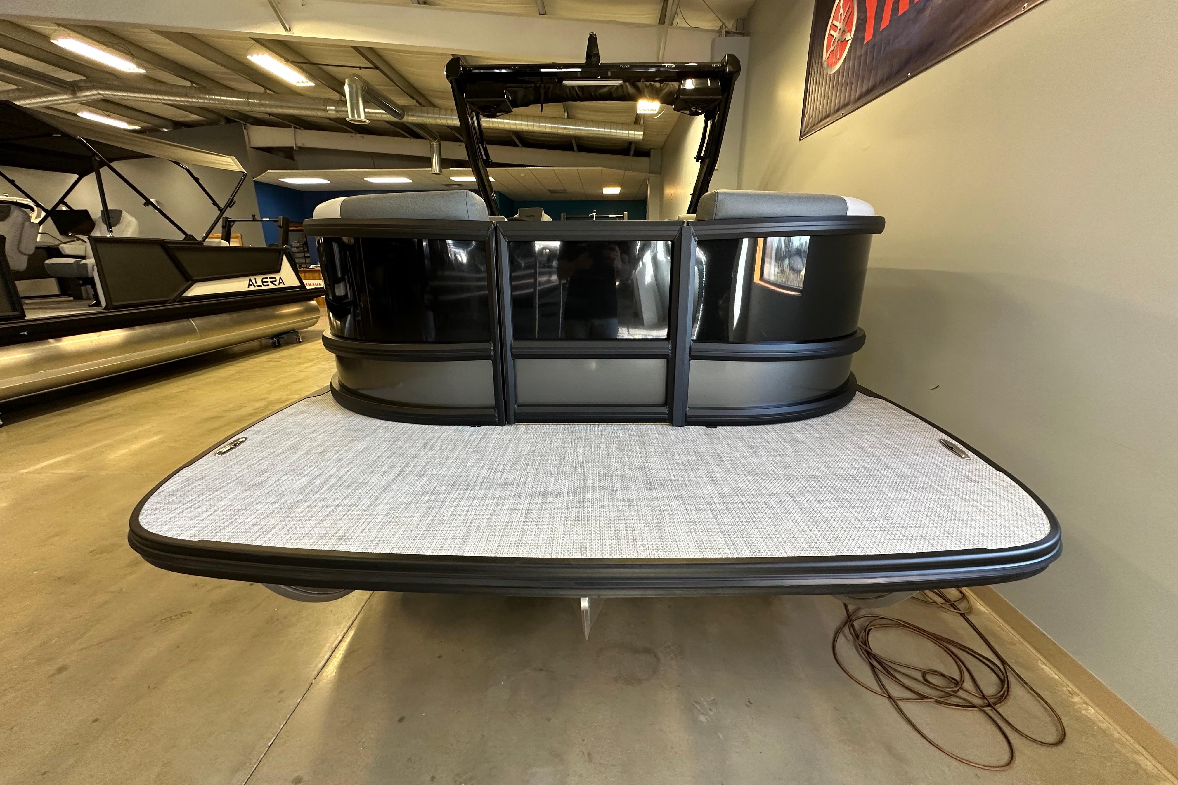 2026 Alera M25L pontoon boat in showroom, rear view with sleek design.
