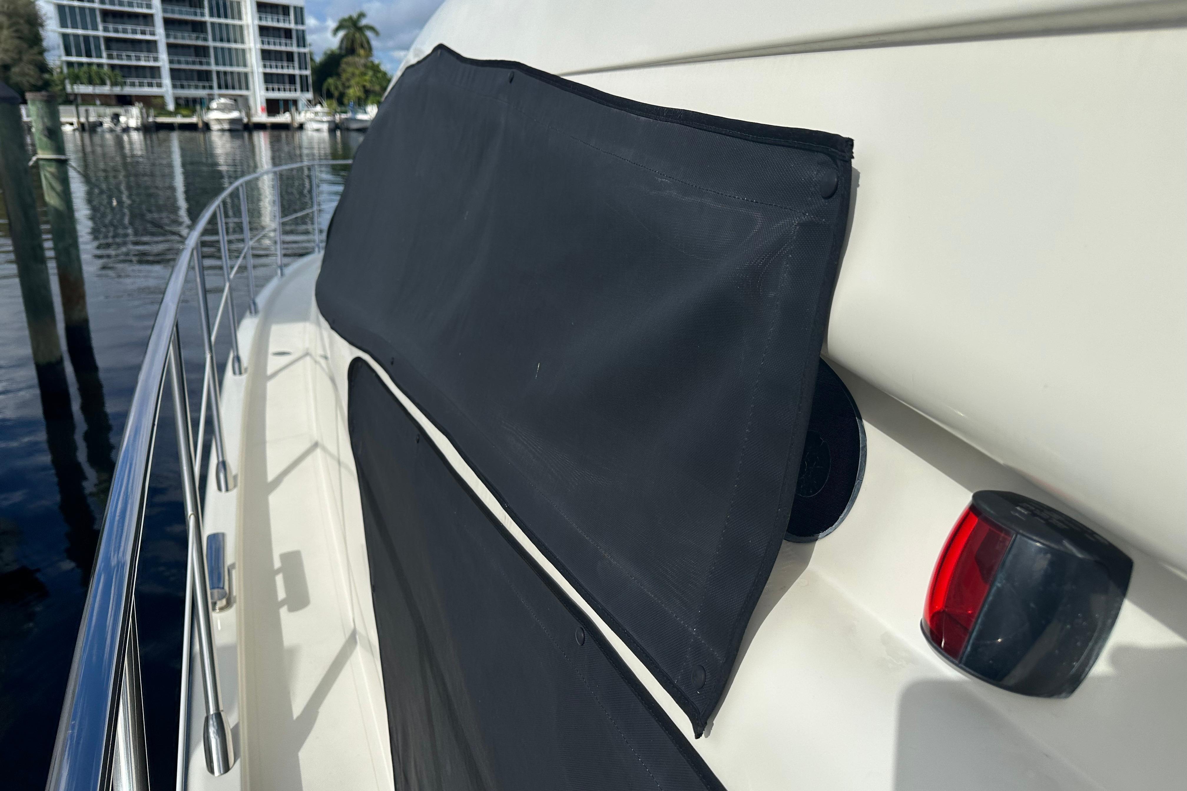 2004 Azimut 55E yacht deck with protective cover and railing, docked near waterfront buildings.