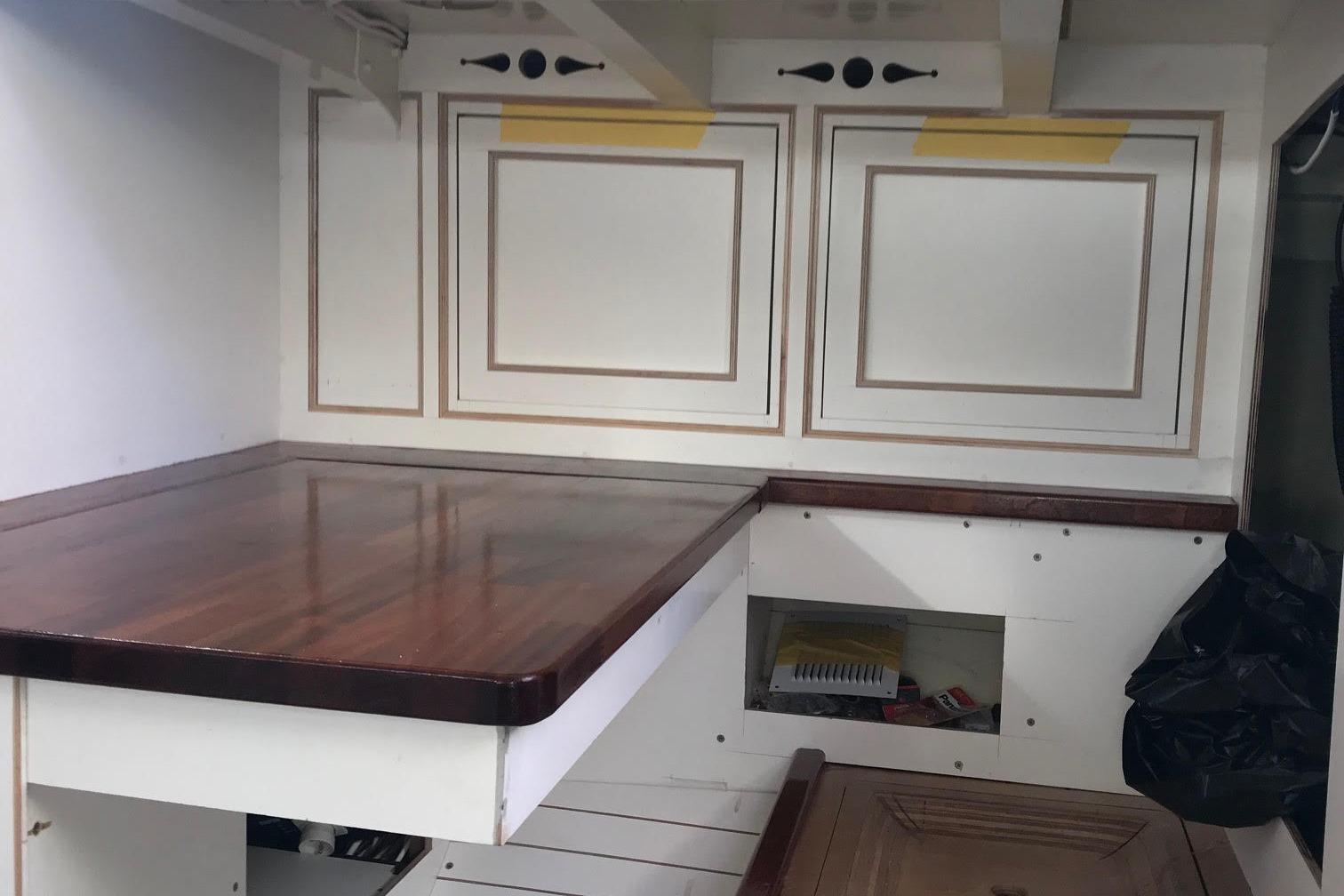 Interior of a 1953 Herreshoff 58 yacht with wooden surfaces and storage compartments.