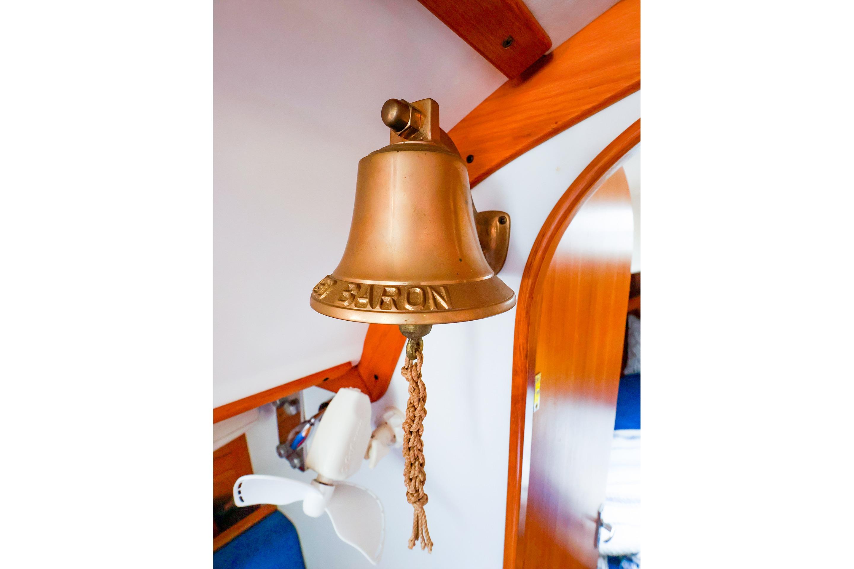 Brass bell inside 2001 J Boats J/32 sailboat, featuring wooden interior accents.