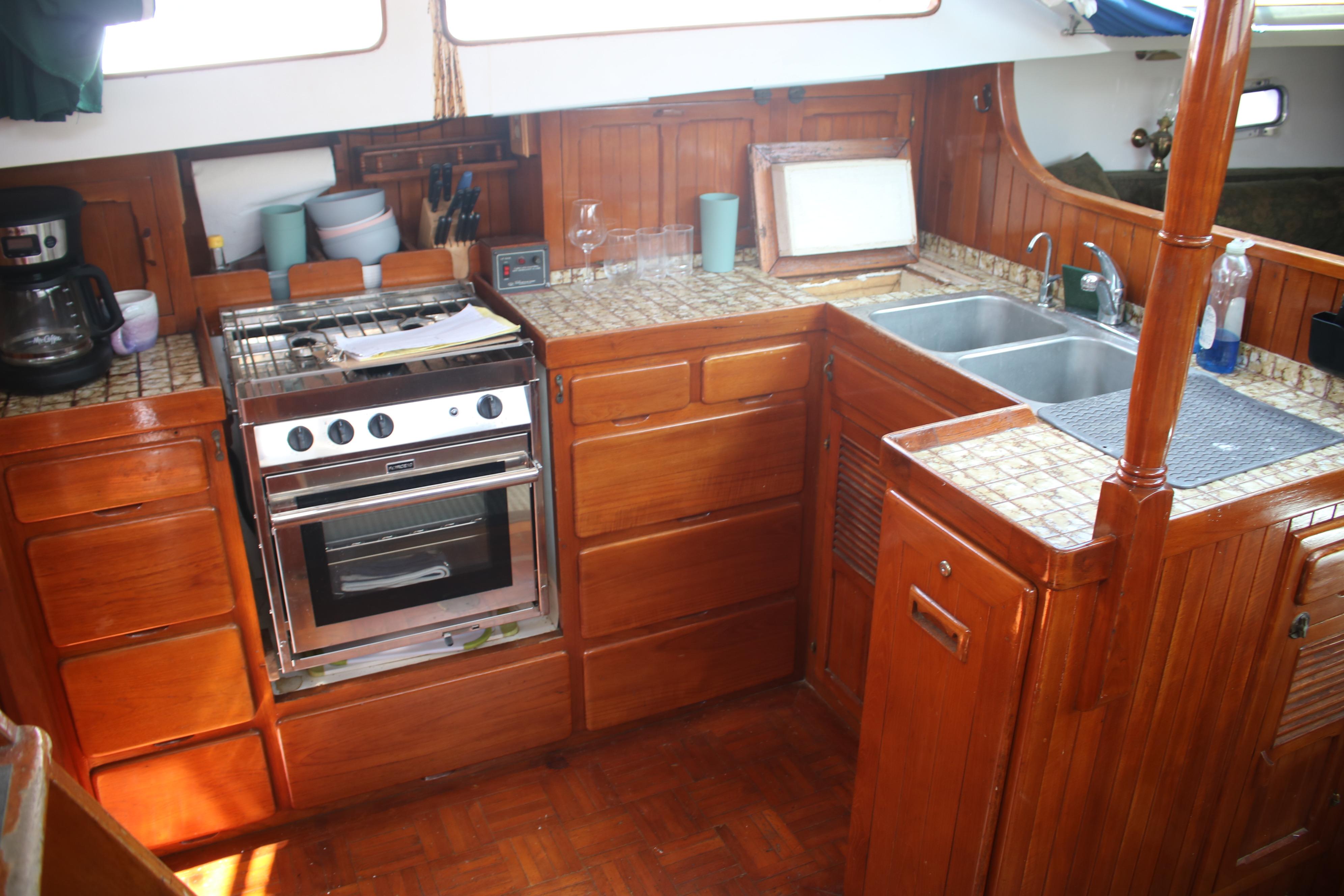 1981 Hardin 45 Voyager yacht kitchen with wooden cabinetry, stove, and double sink.