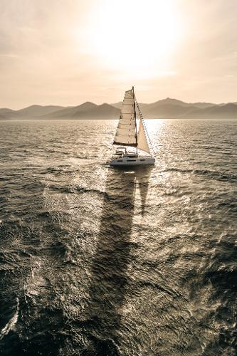 Sailing yacht Lagoon 51 ICONIC 2025 on open sea at sunset.