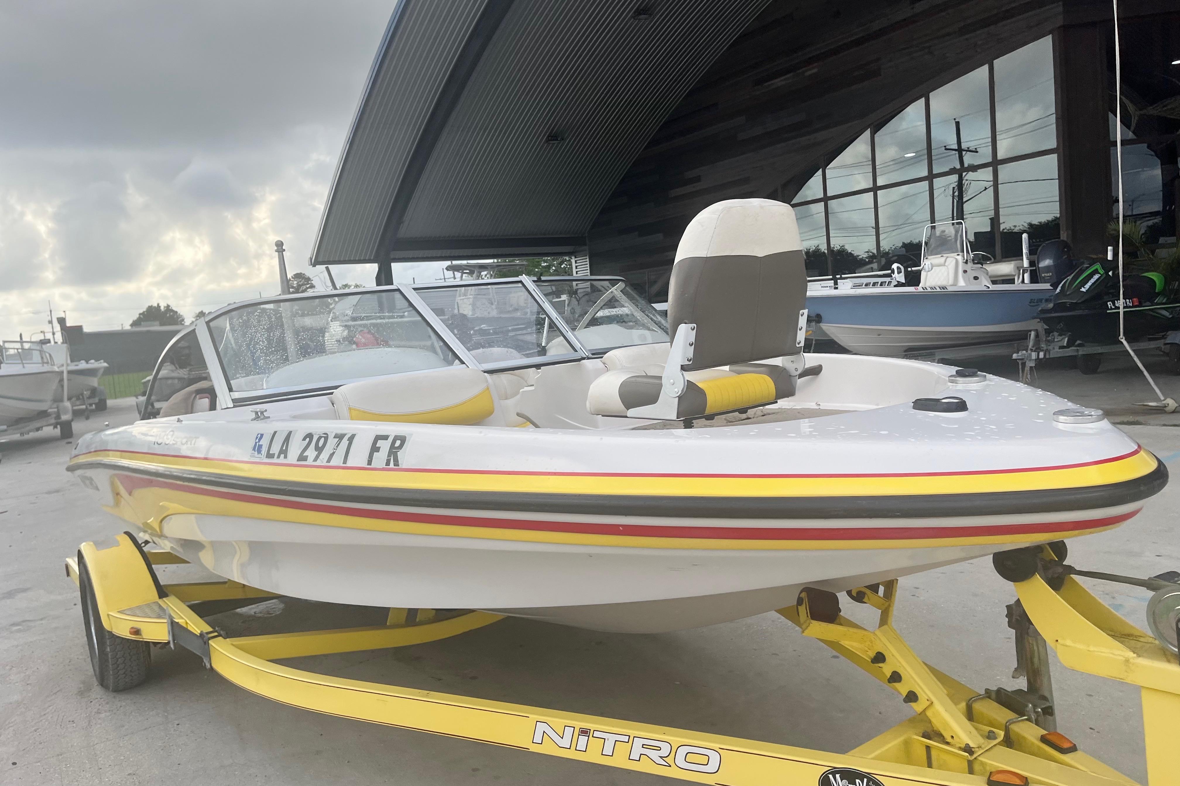 2006 Nitro 189 Sport boat on trailer, parked outdoors near a modern building.