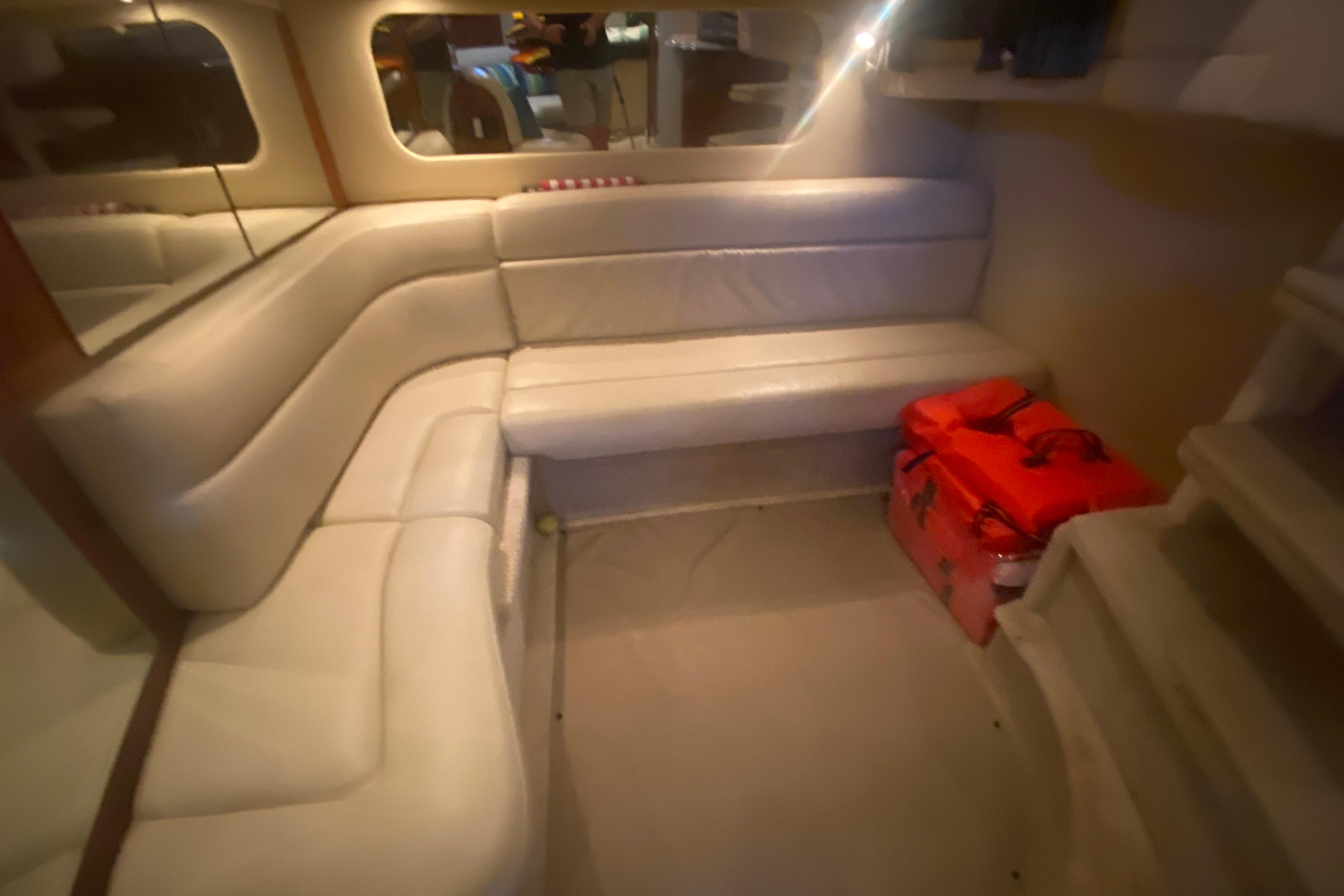 Interior of 2004 Sea Ray 380 Sundancer with white leather seating and red bags.