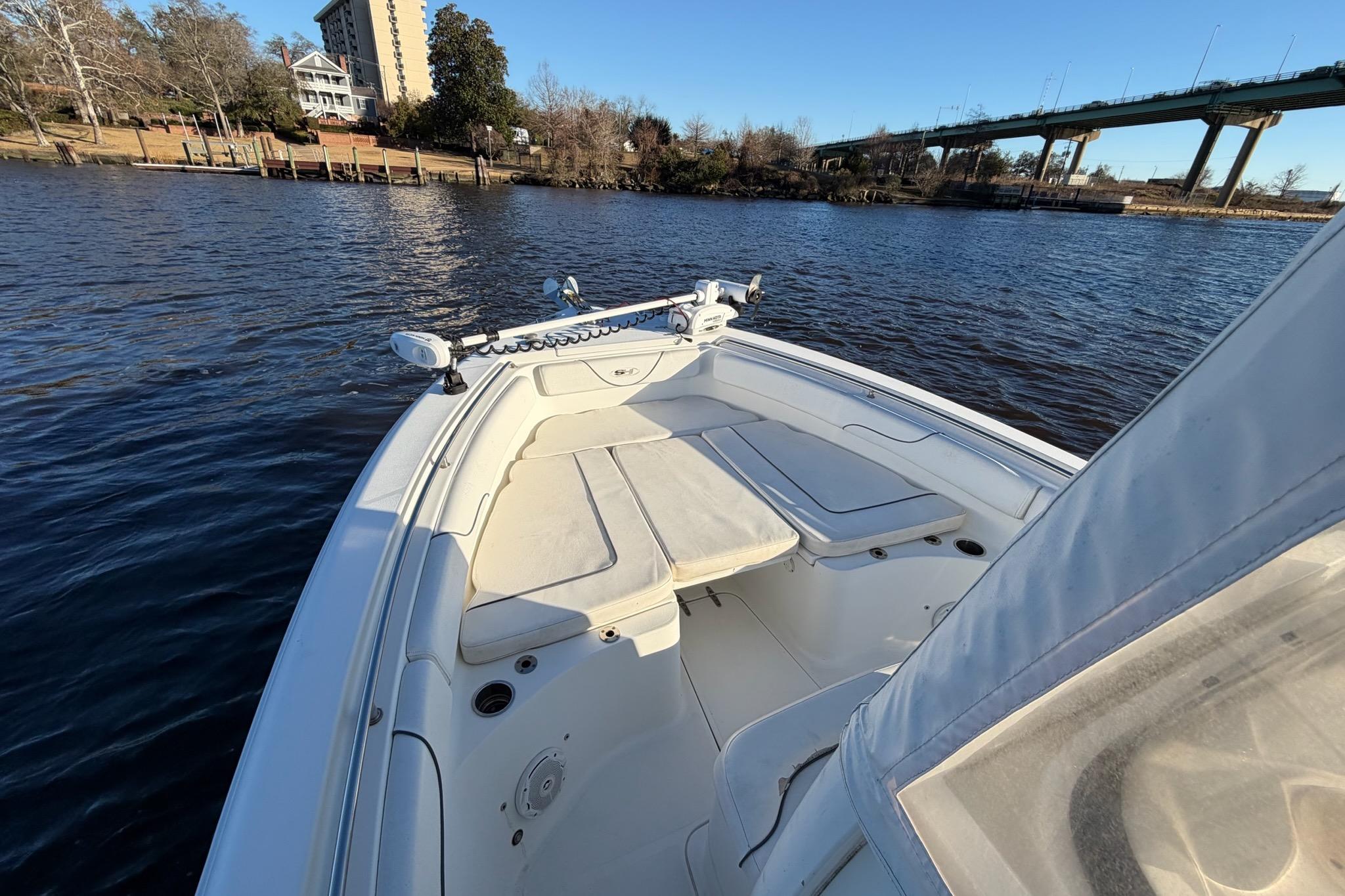 2015 Sea Hunt Gamefish 25 boat on calm water near a bridge and shoreline.