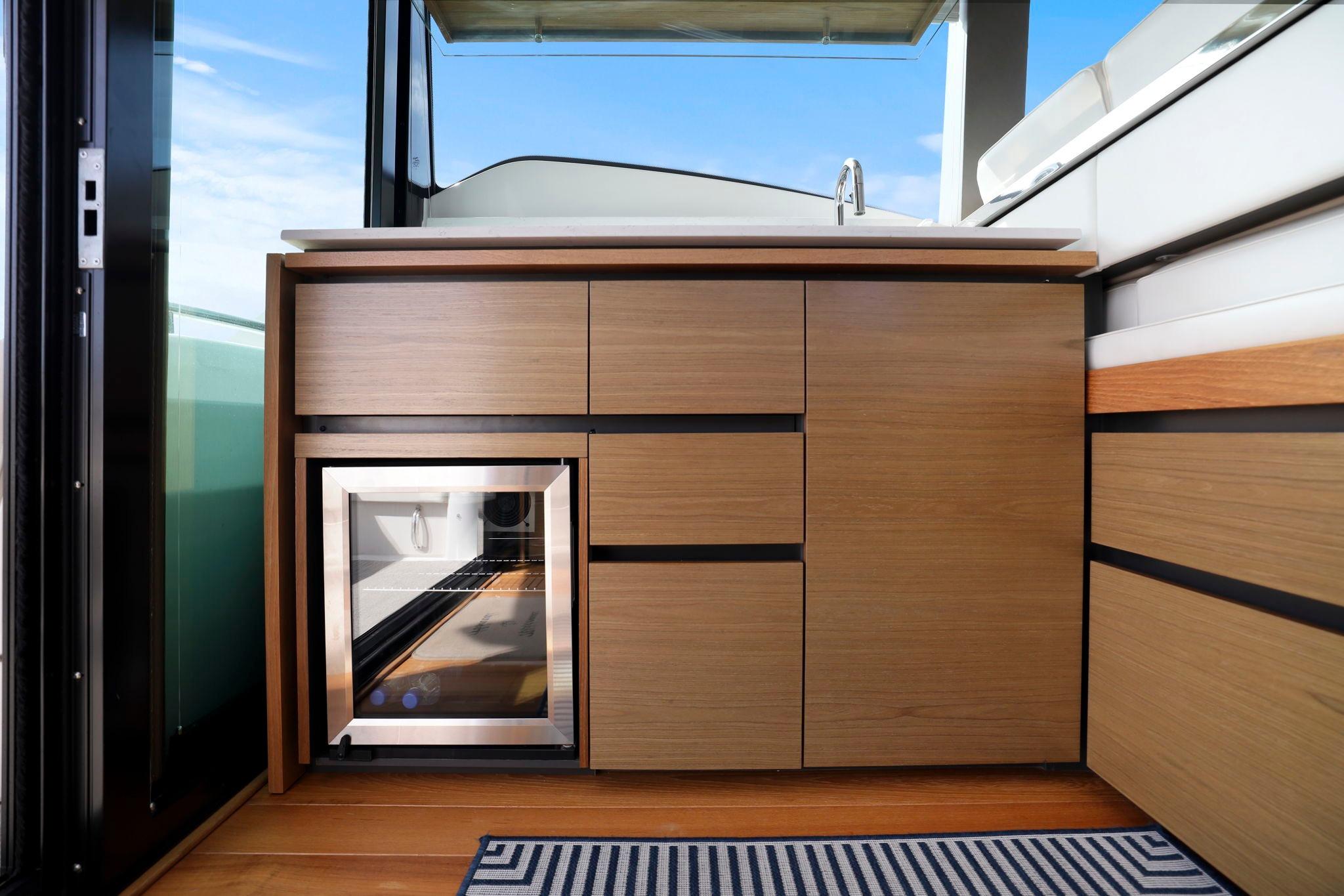2023 Tiara Yachts C49 Coupe interior with sleek wooden cabinetry and mini fridge.