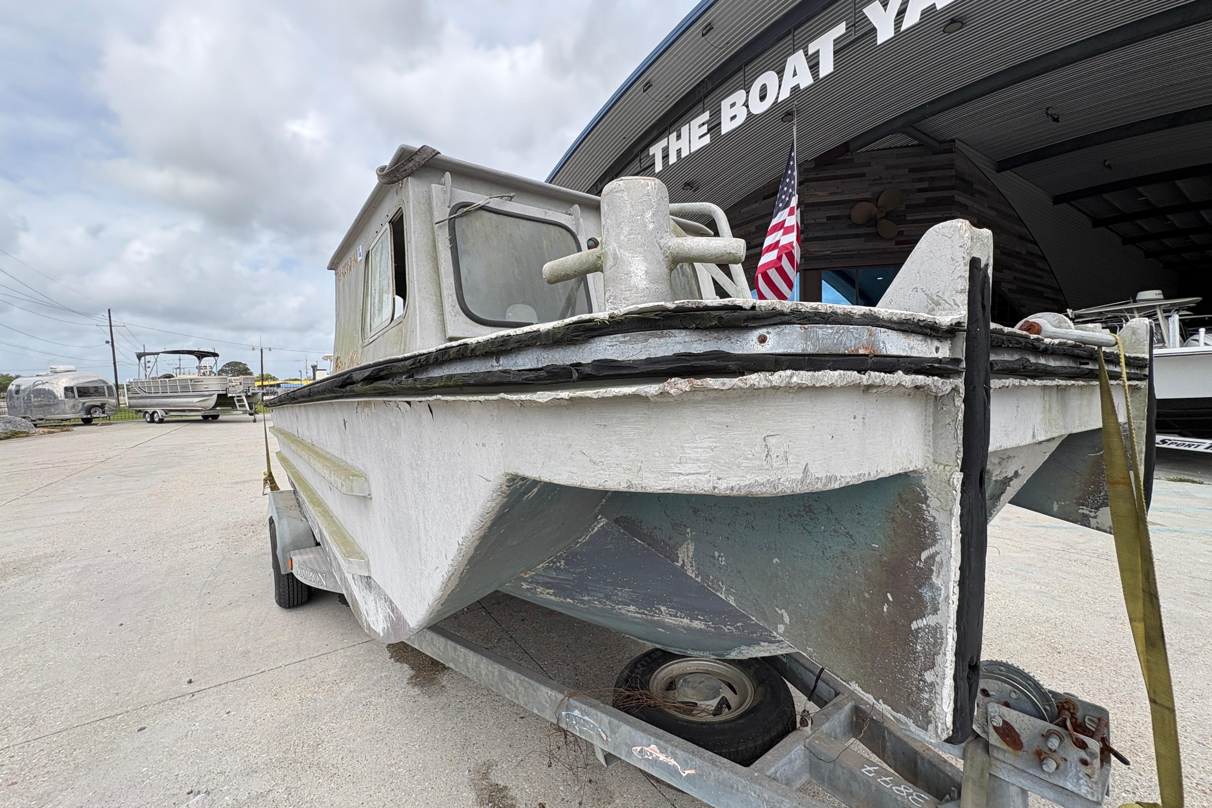 Vintage 1972 custom 23' work/push boat on trailer at boat yard.
