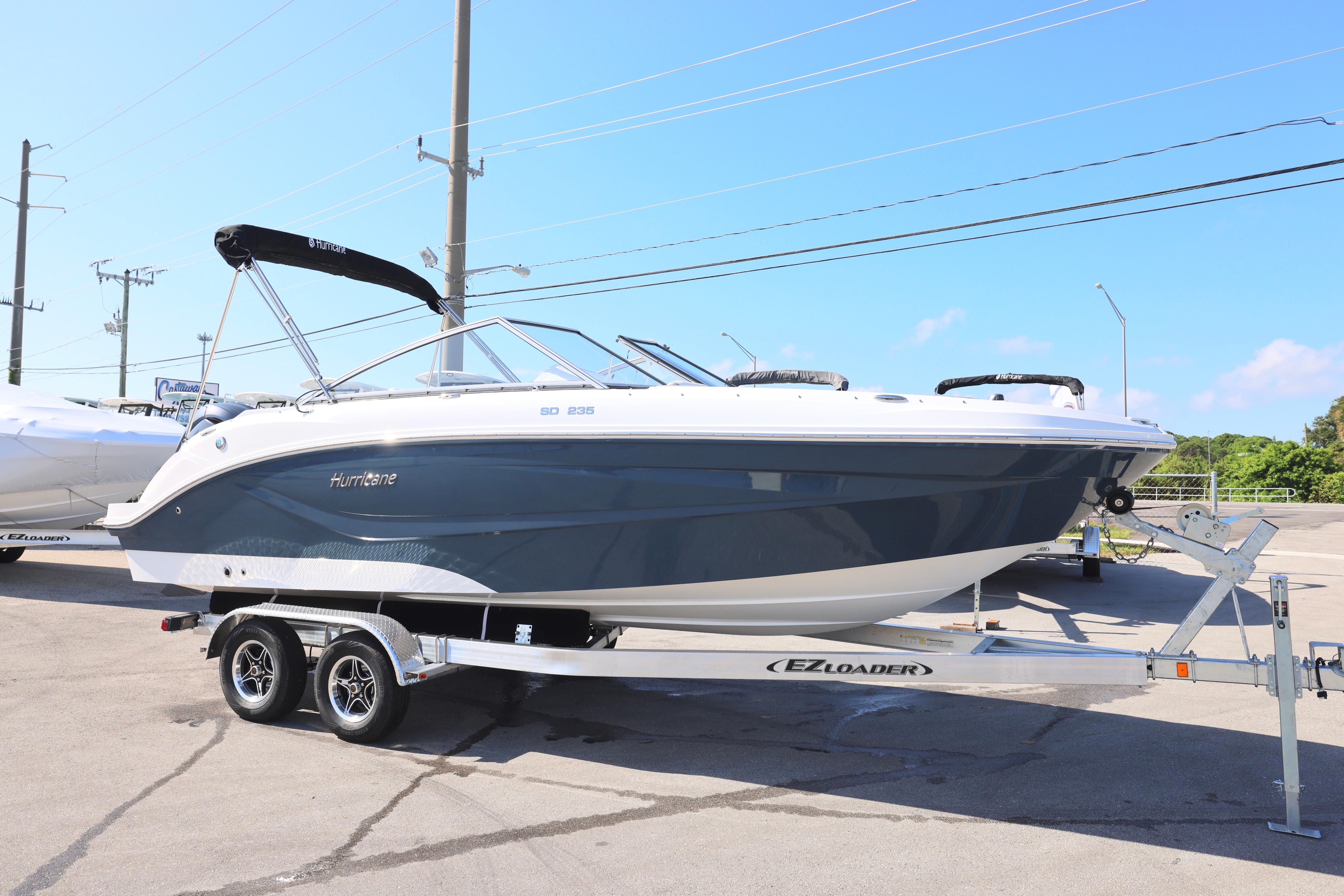 2026 Hurricane SunDeck 235 OB boat on trailer, parked outdoors under clear sky.