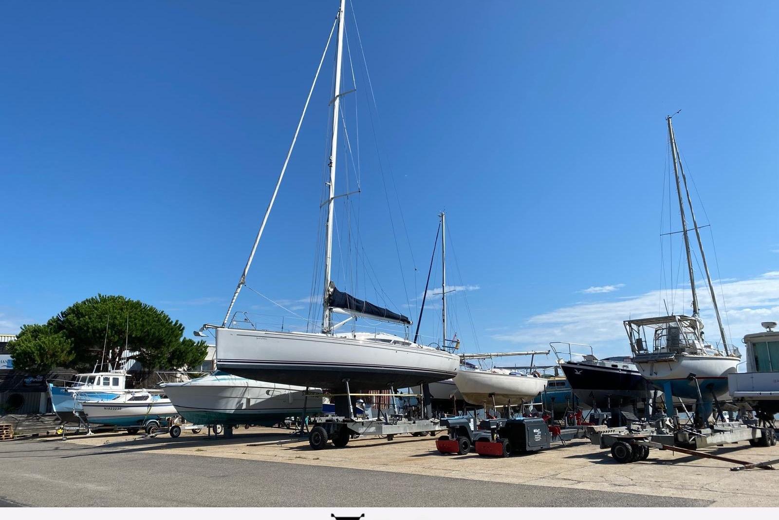 Sailboats, including a 2010 Maxi 1300, on trailers under a clear blue sky.