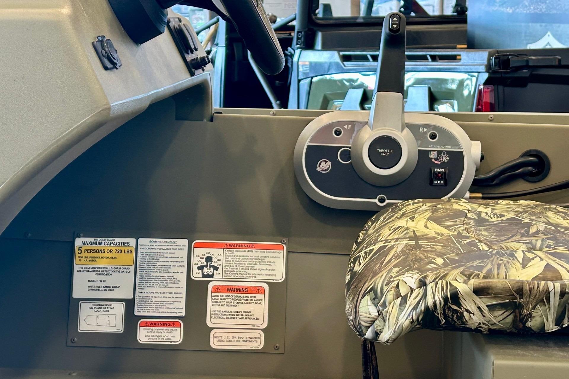 Control panel and seat of 2026 Tracker Grizzly 1754 SC boat, featuring capacity warnings.