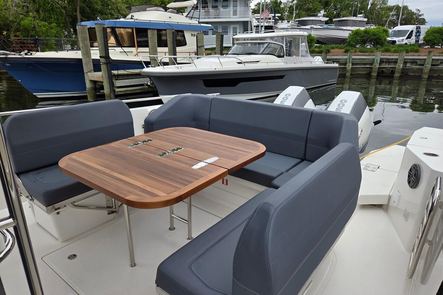 2023 Nimbus Tender 11 boat with sleek seating and wooden table docked at marina.