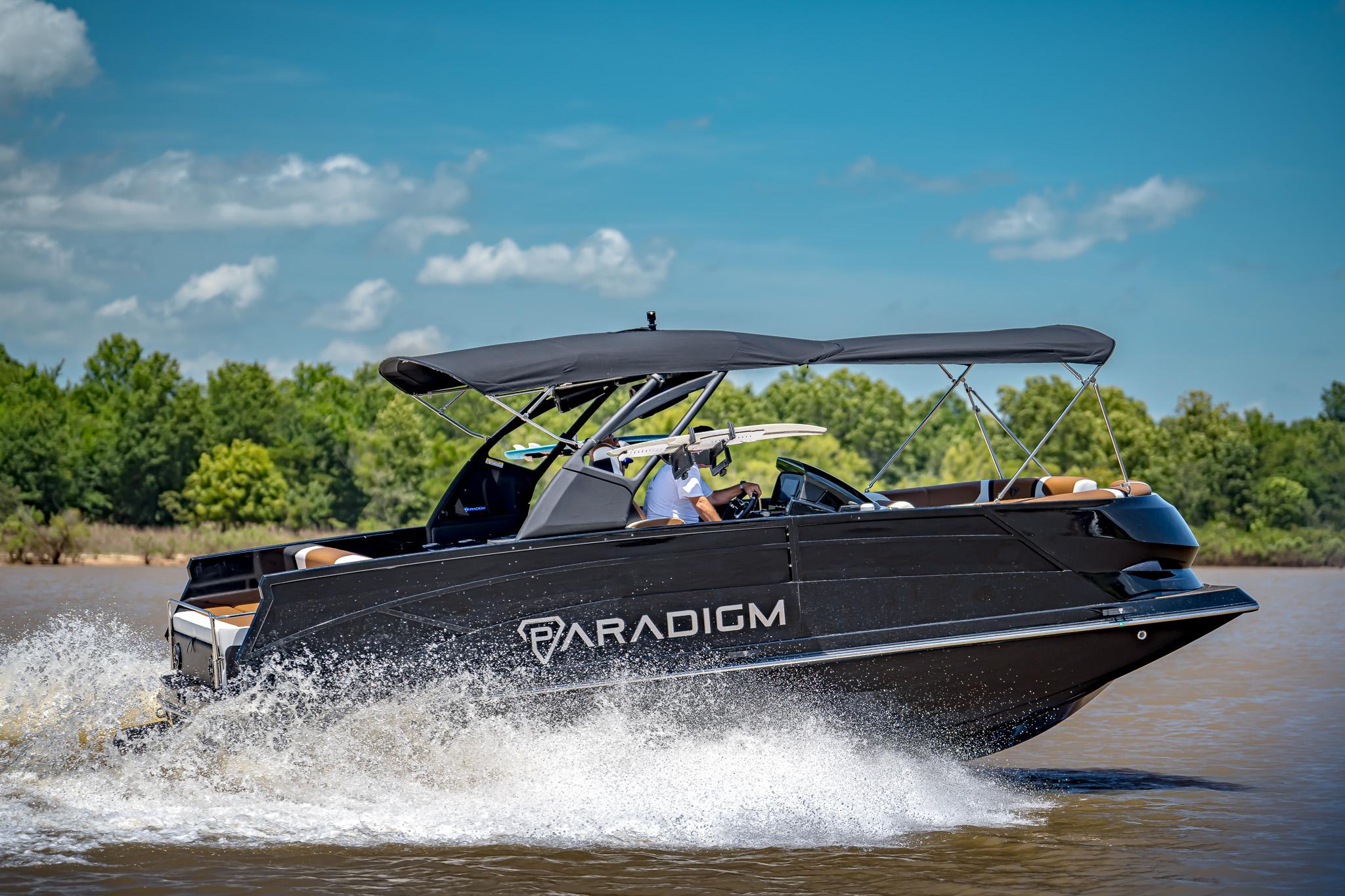 2025 Paradigm 236 boat cruising on a sunny day, surrounded by lush greenery.