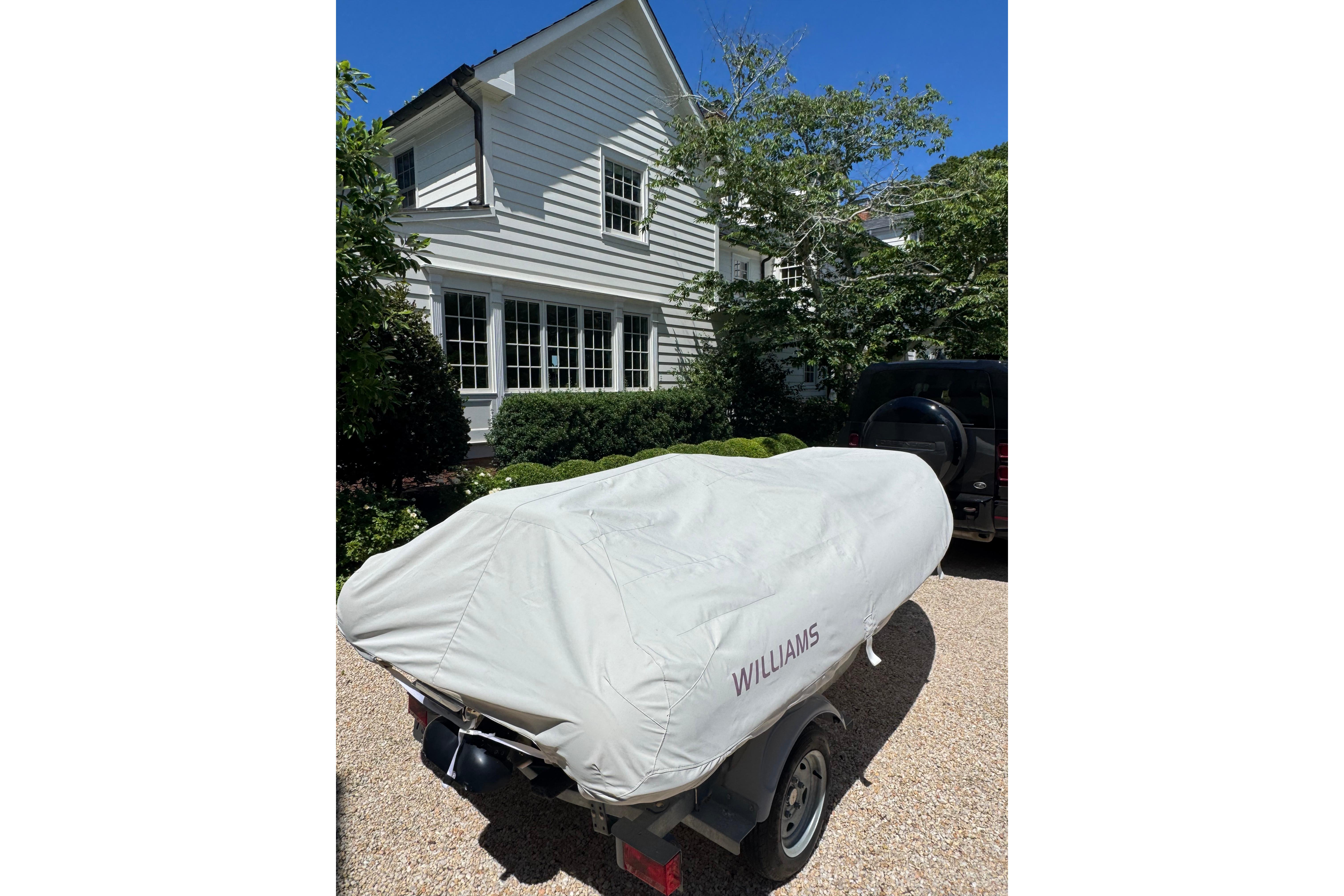 Covered 2017 Williams Jet Tenders Turbojet 325 on trailer, parked in front of a house.