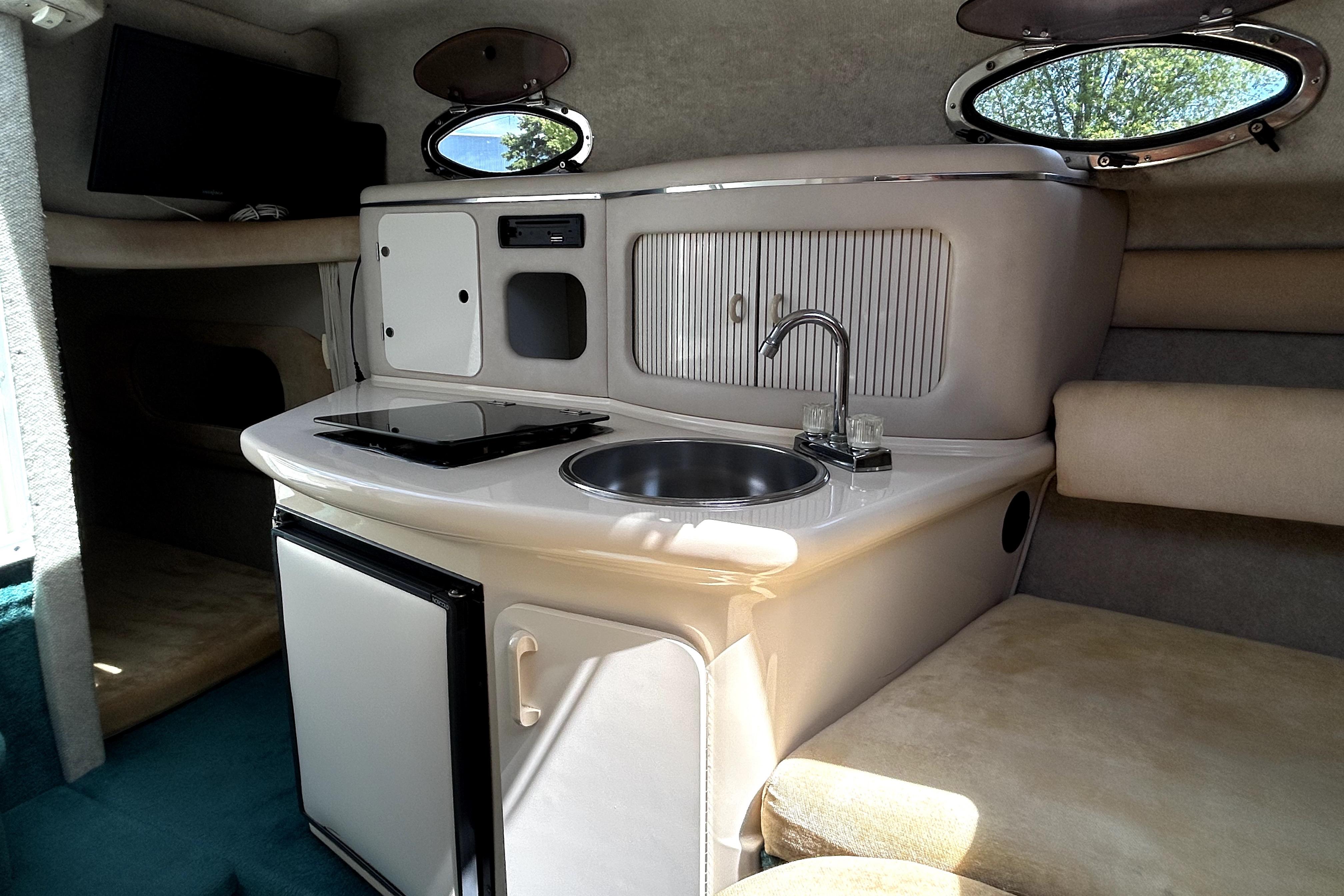 Interior of a 1995 Sea Ray 250 Sundancer boat with kitchenette and seating area.