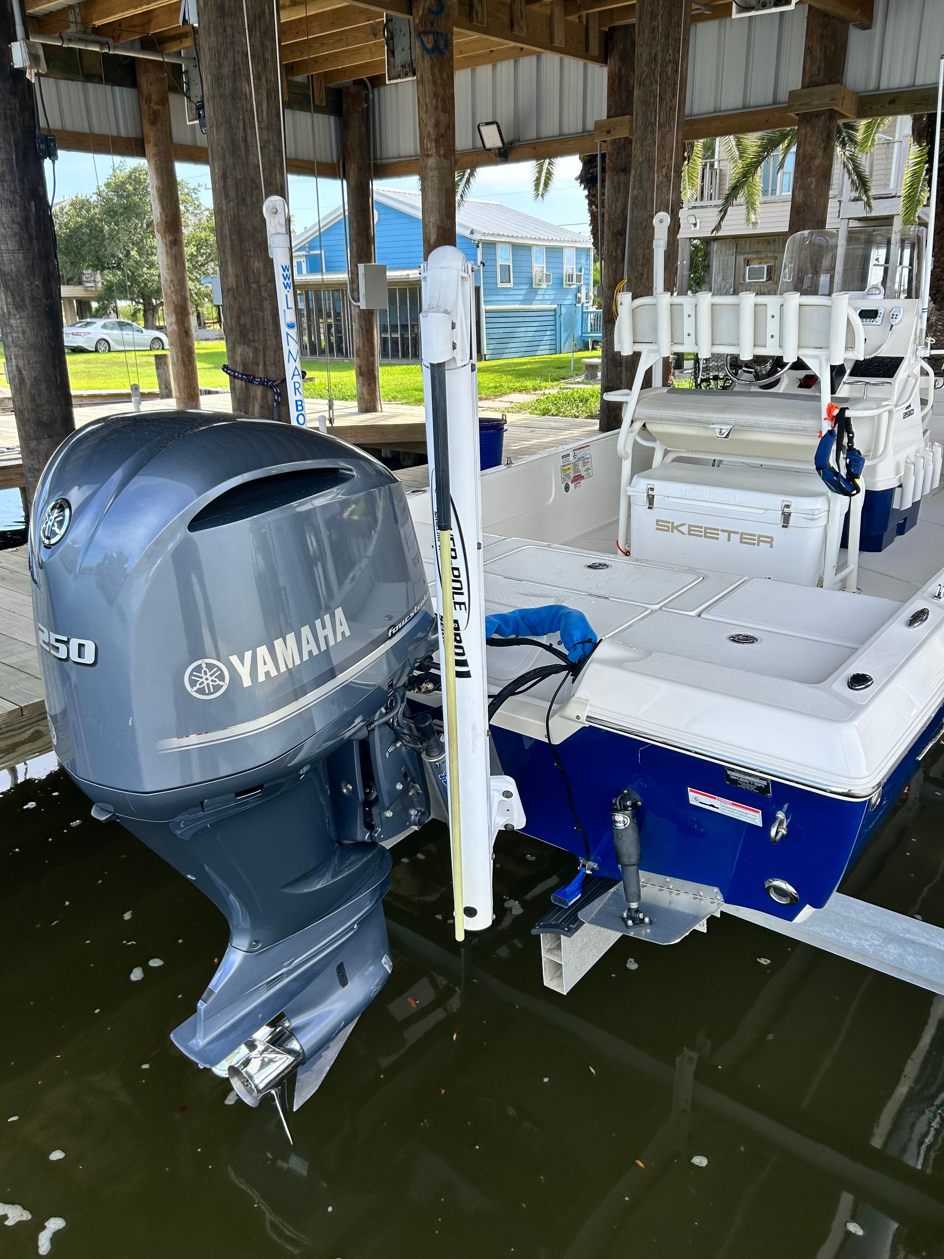A 2016 Skeeter SX230 boat with a Yamaha 250 outboard motor, docked under a covered area.