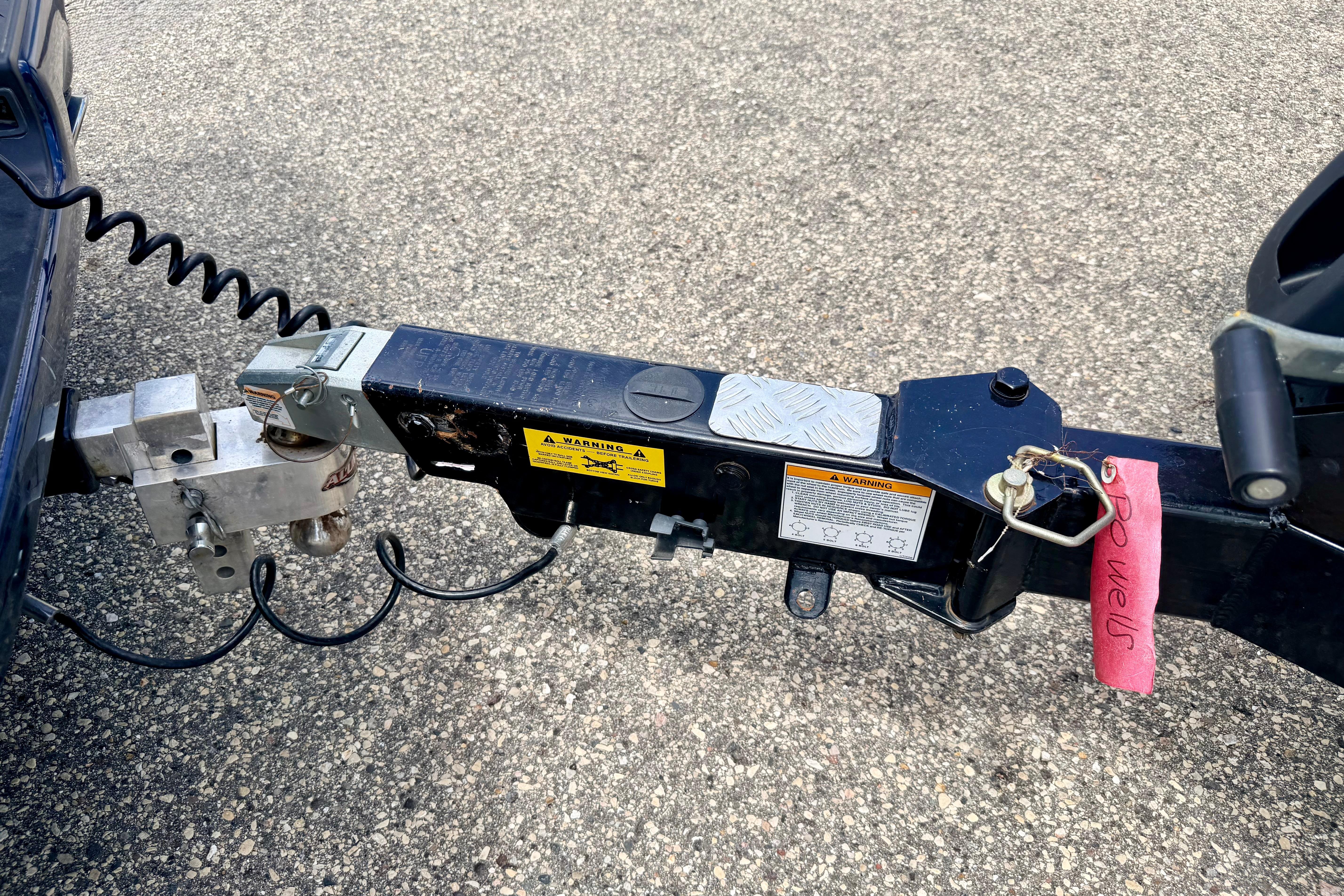 Trailer hitch of a 2014 Tigé R20 boat on asphalt surface.