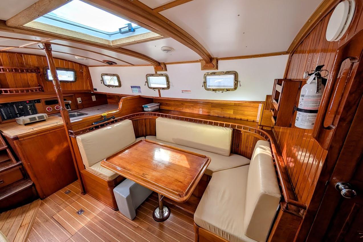 Interior of 1980 Island Trader 38 sailboat with wooden furnishings and cozy seating area.