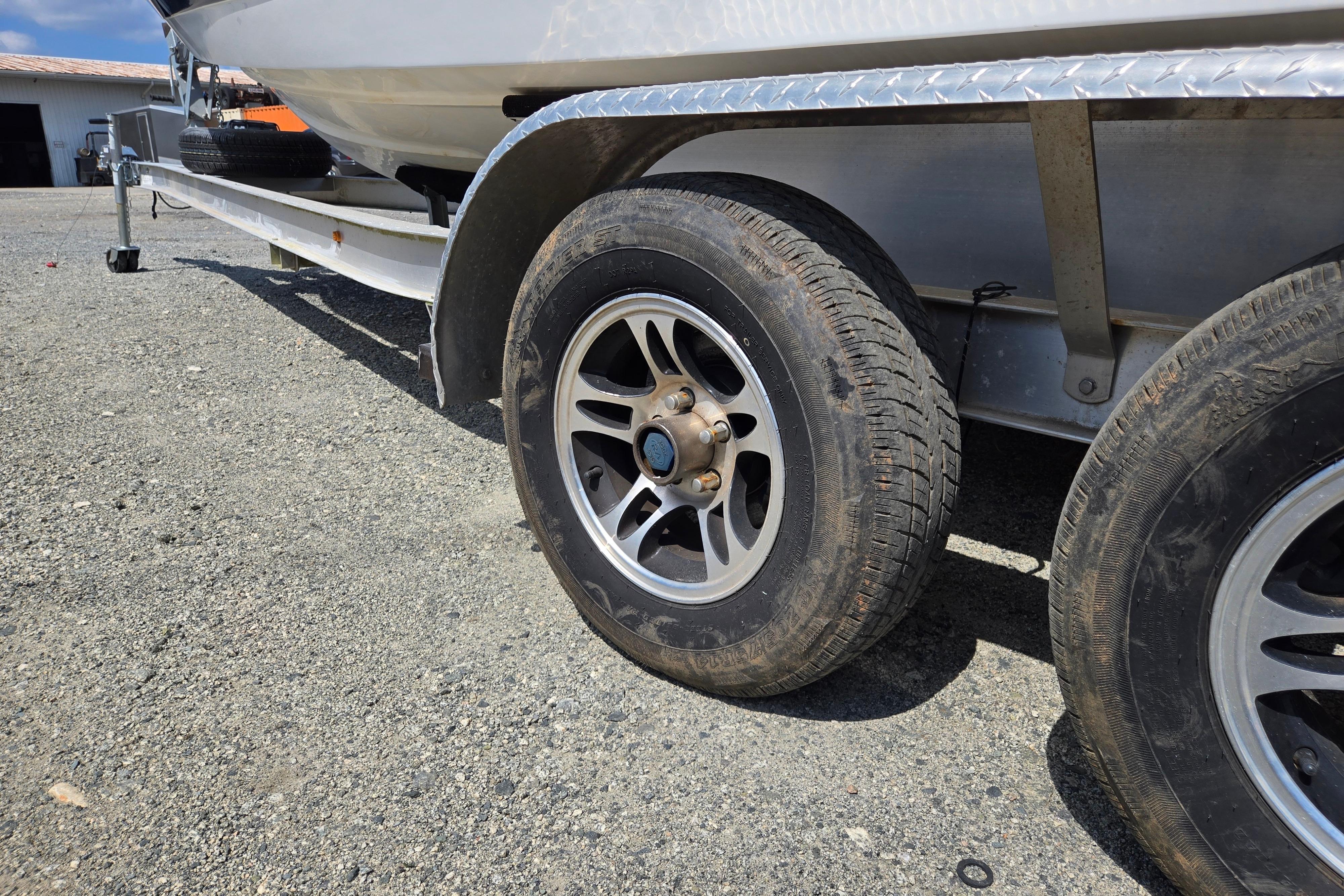 Trailer wheels of a 2000 Cobalt 246 boat on gravel surface.