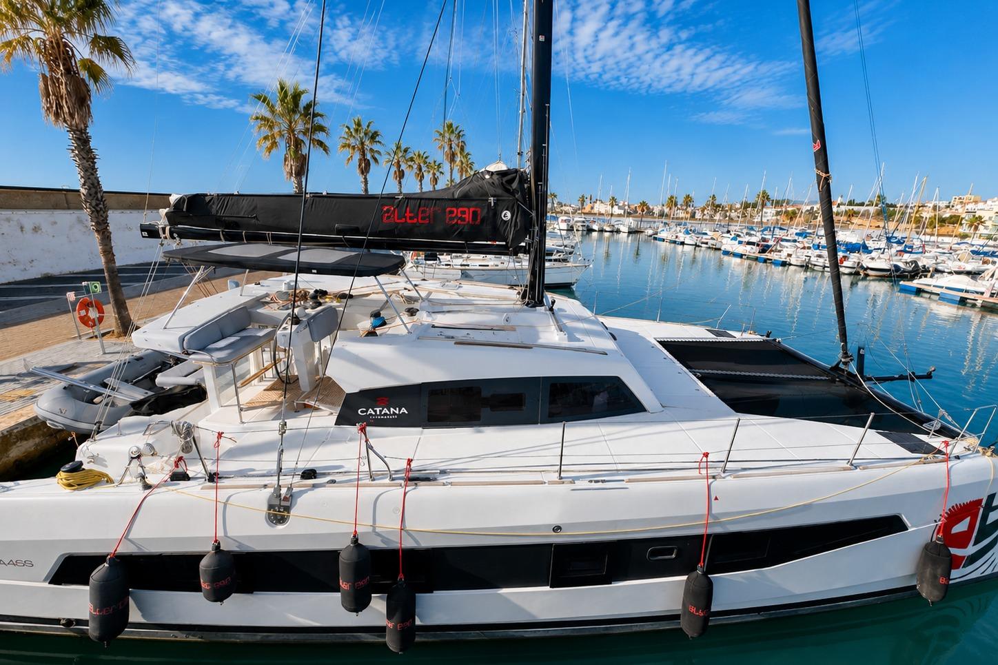 2023 Catana 50 catamaran docked in a sunny marina with palm trees.