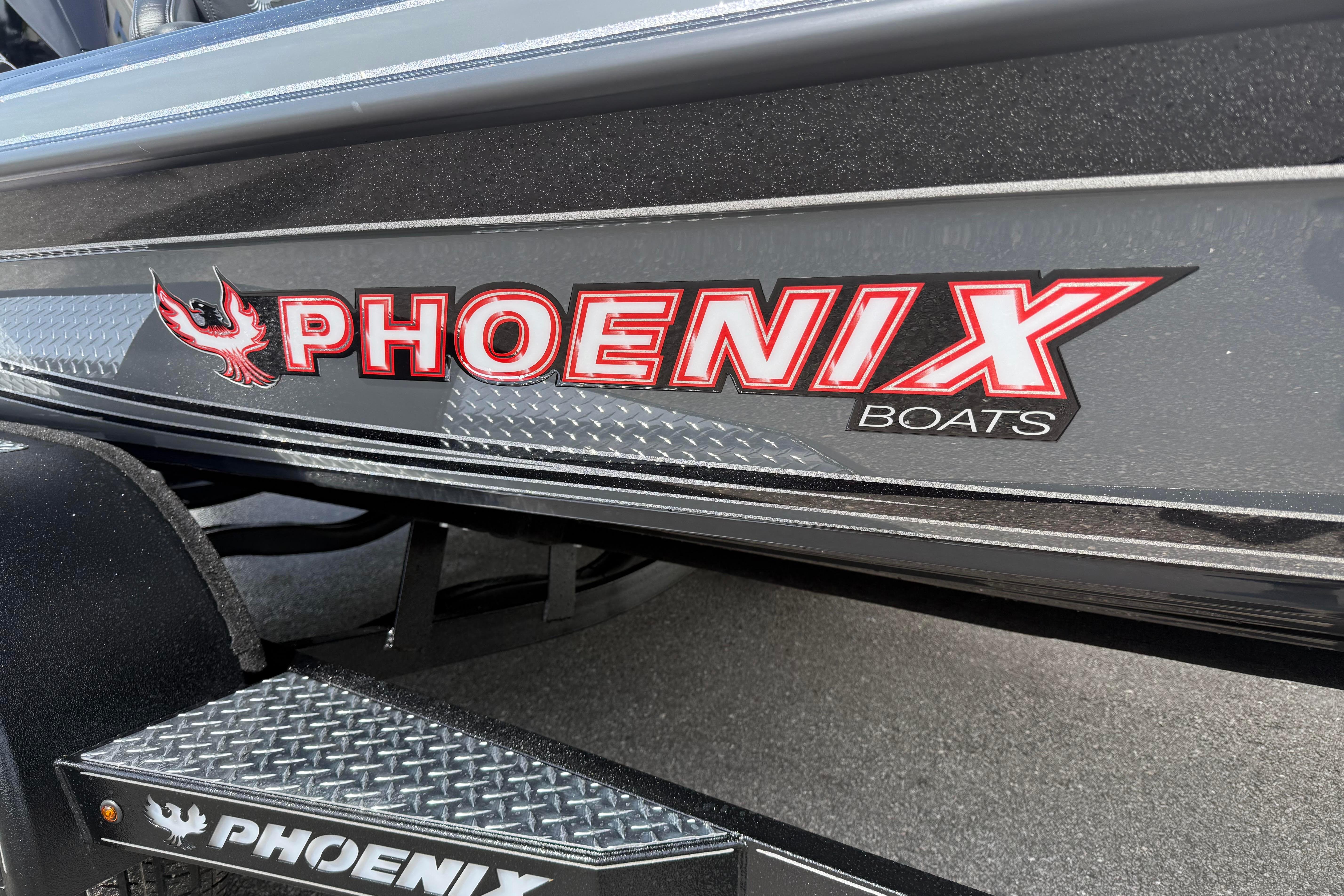 Close-up of 2027 Phoenix 921 Elite X boat logo on sleek black surface.