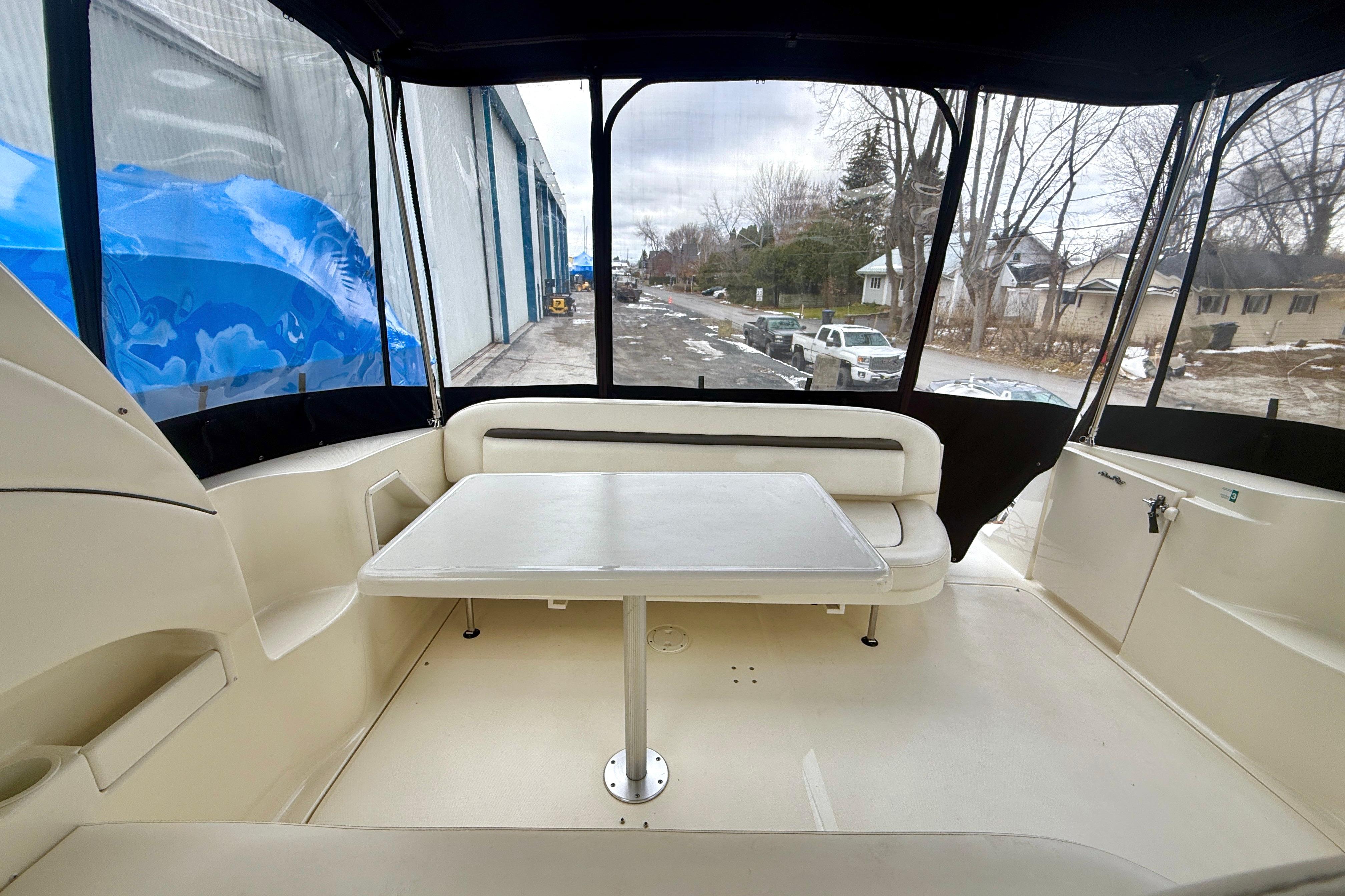 2004 Searay 360 Sundancer boat interior with seating and table, docked near a road.