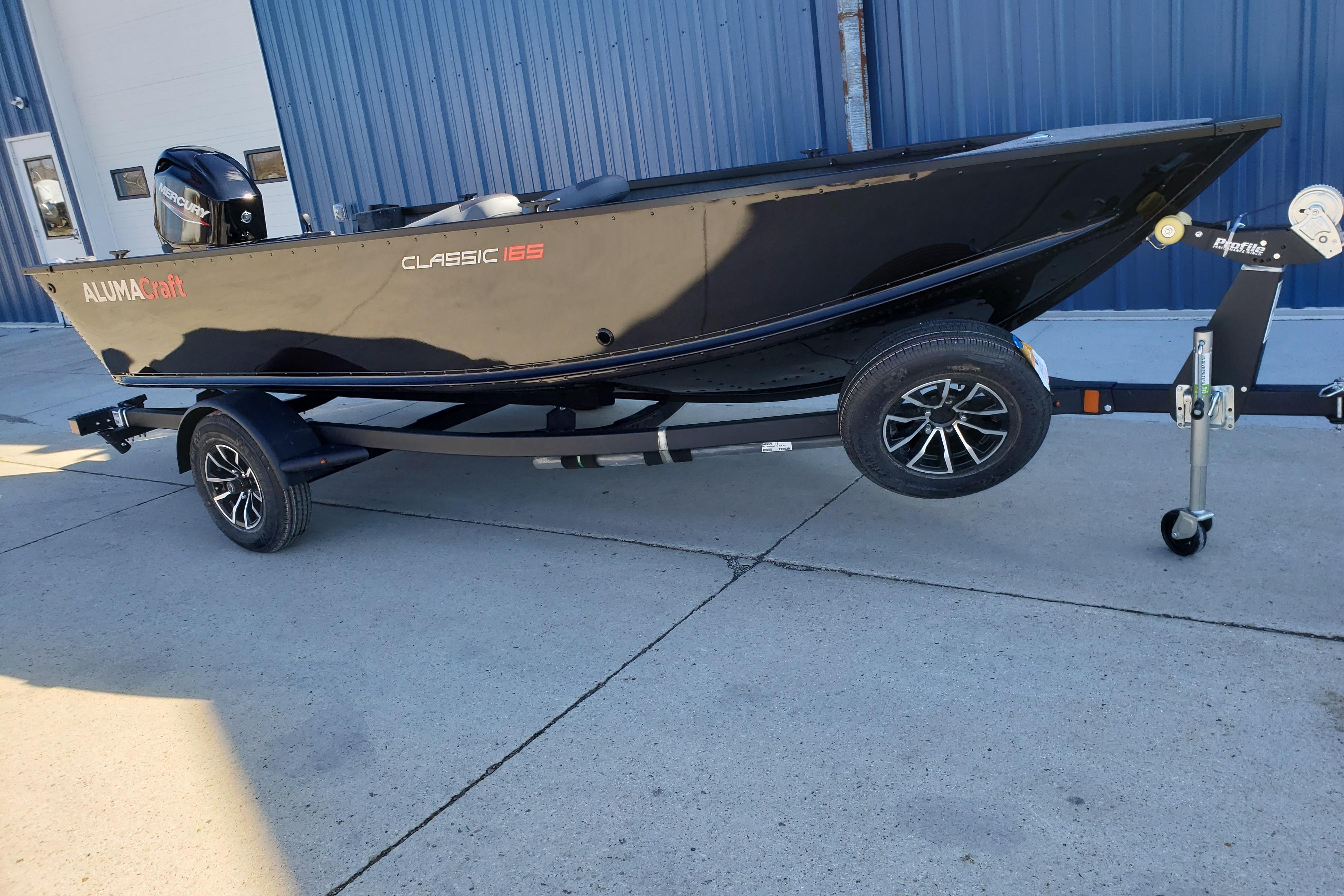 2026 Alumacraft Classic 165 Tiller boat on trailer, parked outdoors.