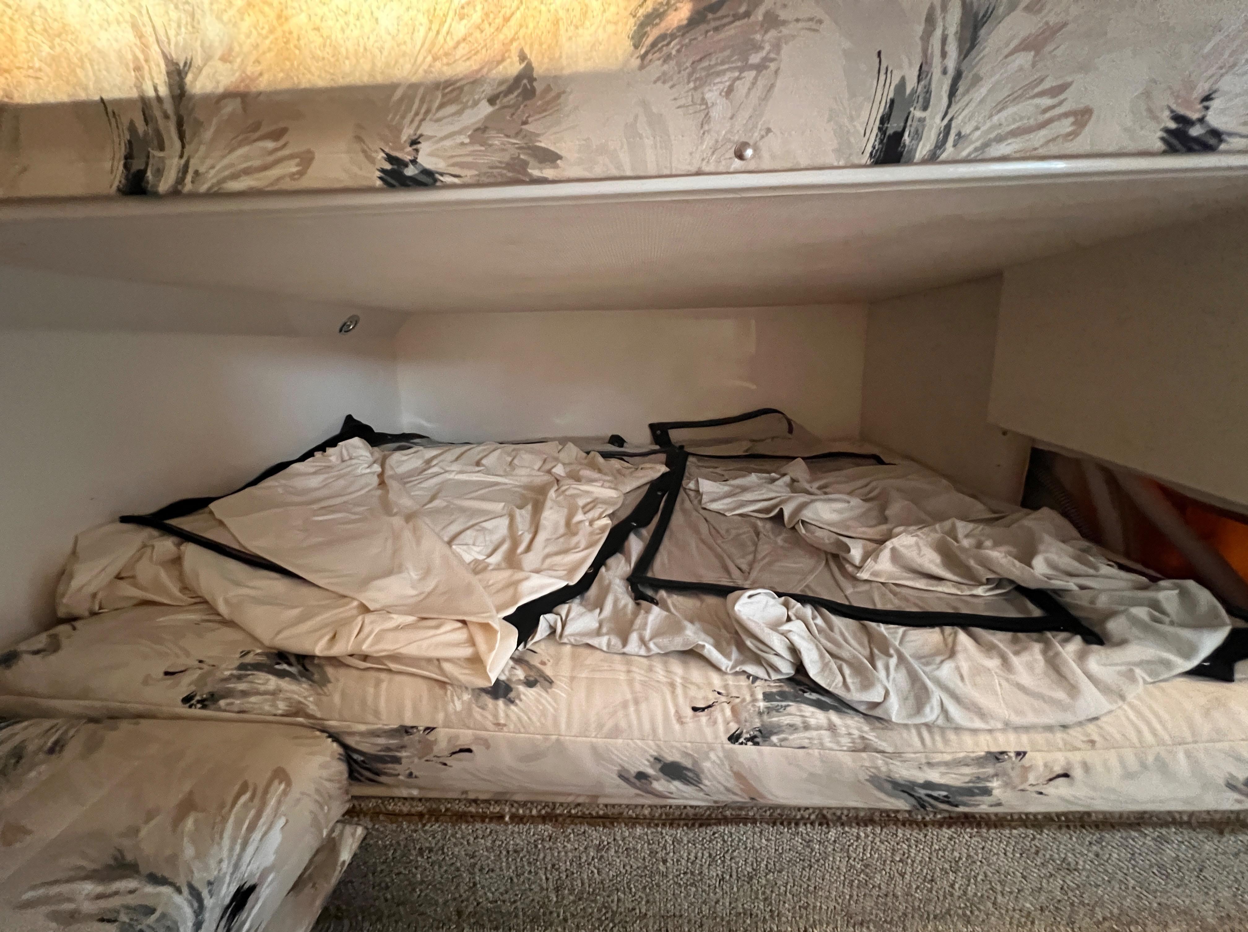 Interior cabin of 2000 Wellcraft 45 Excalibur with unmade bed and floral upholstery.