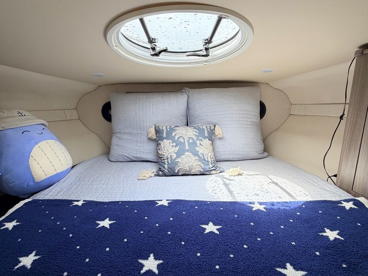 Cozy cabin with a bed, decorative pillows, and a round skylight.