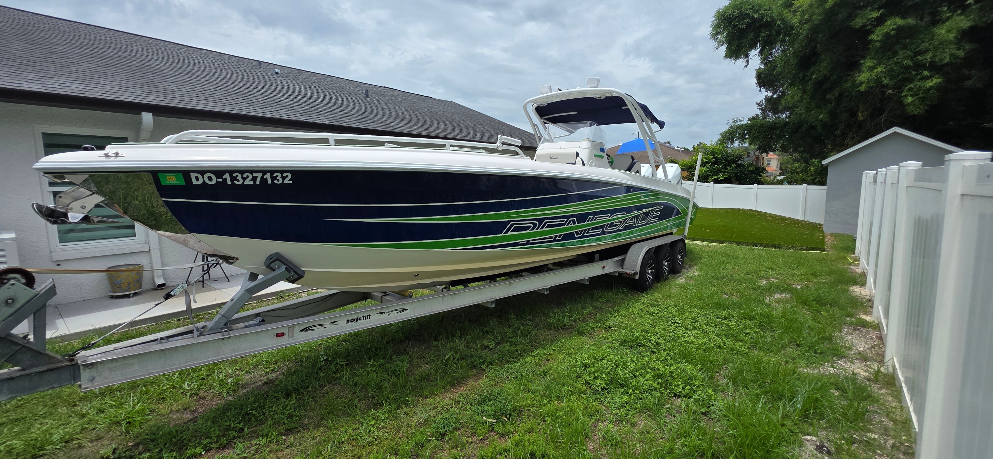 2013 Renegade 32 FT boat on trailer in yard.
