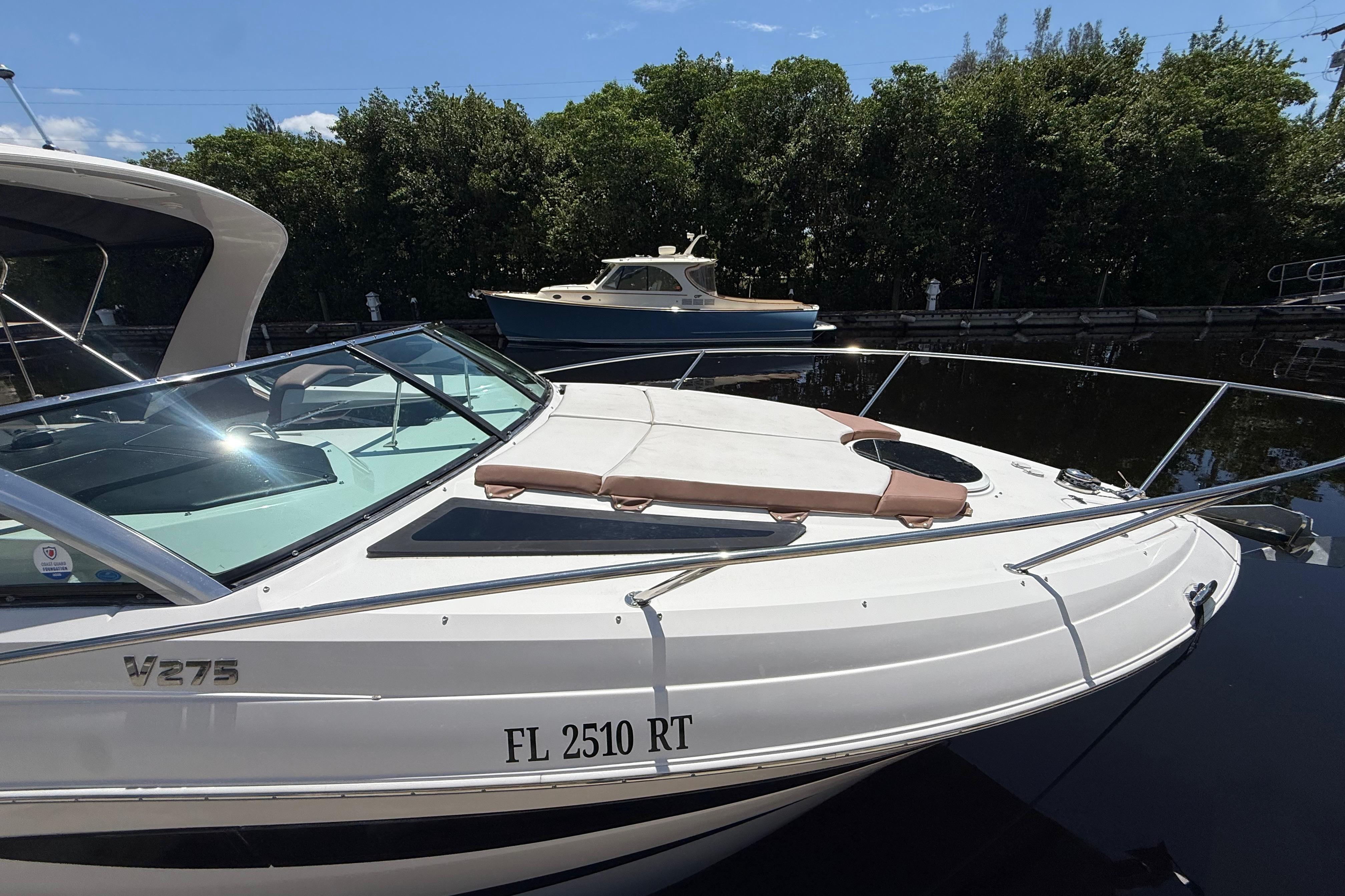 2017 Four Winns V275 boat docked on a sunny day with lush greenery background.