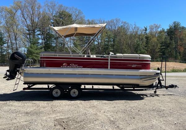 2025 Sun Tracker Party Barge 22 RF DLX pontoon boat on trailer, parked outdoors.
