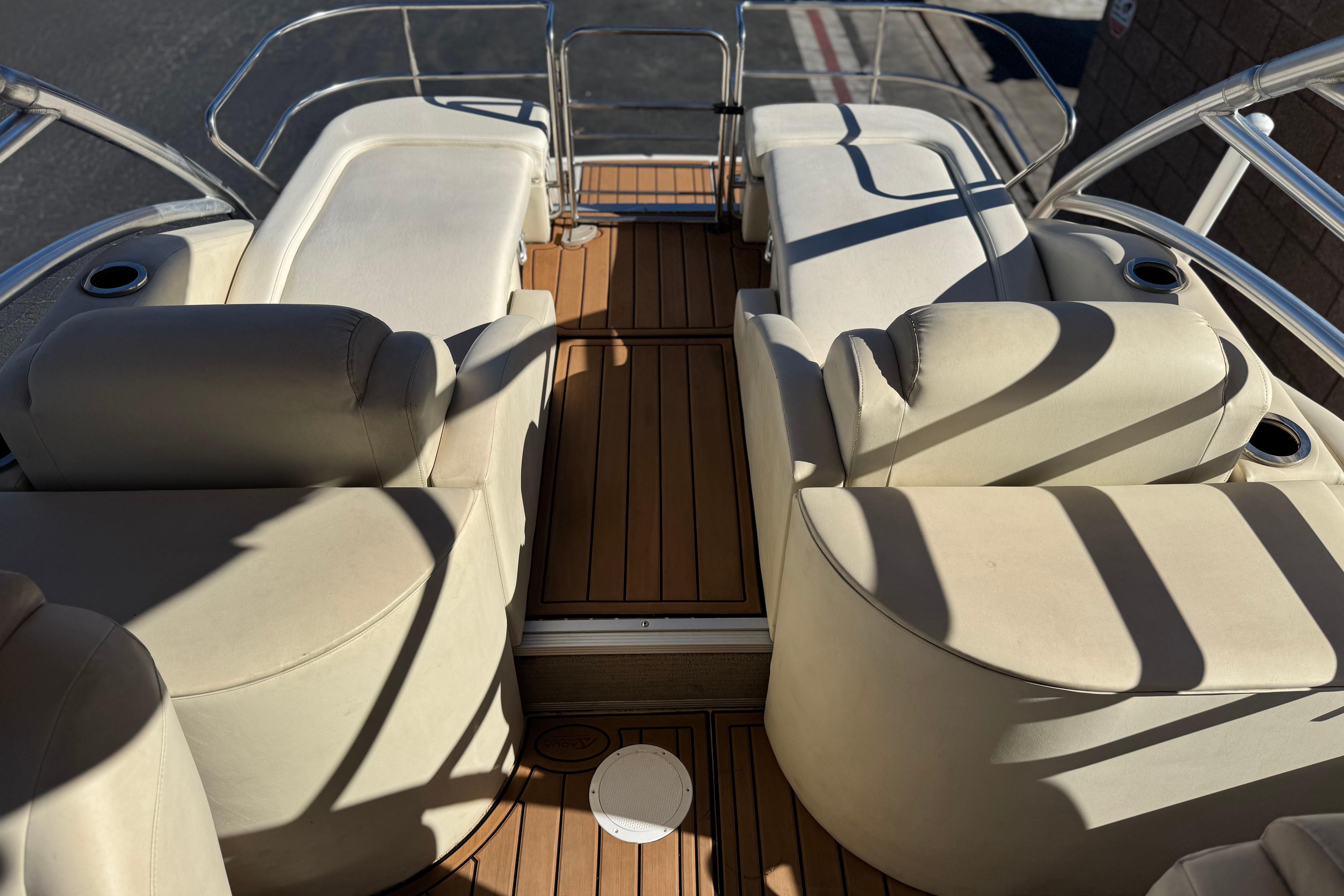 Interior of 2013 Bennington 2575QCW I/O boat with beige seating and wooden flooring.