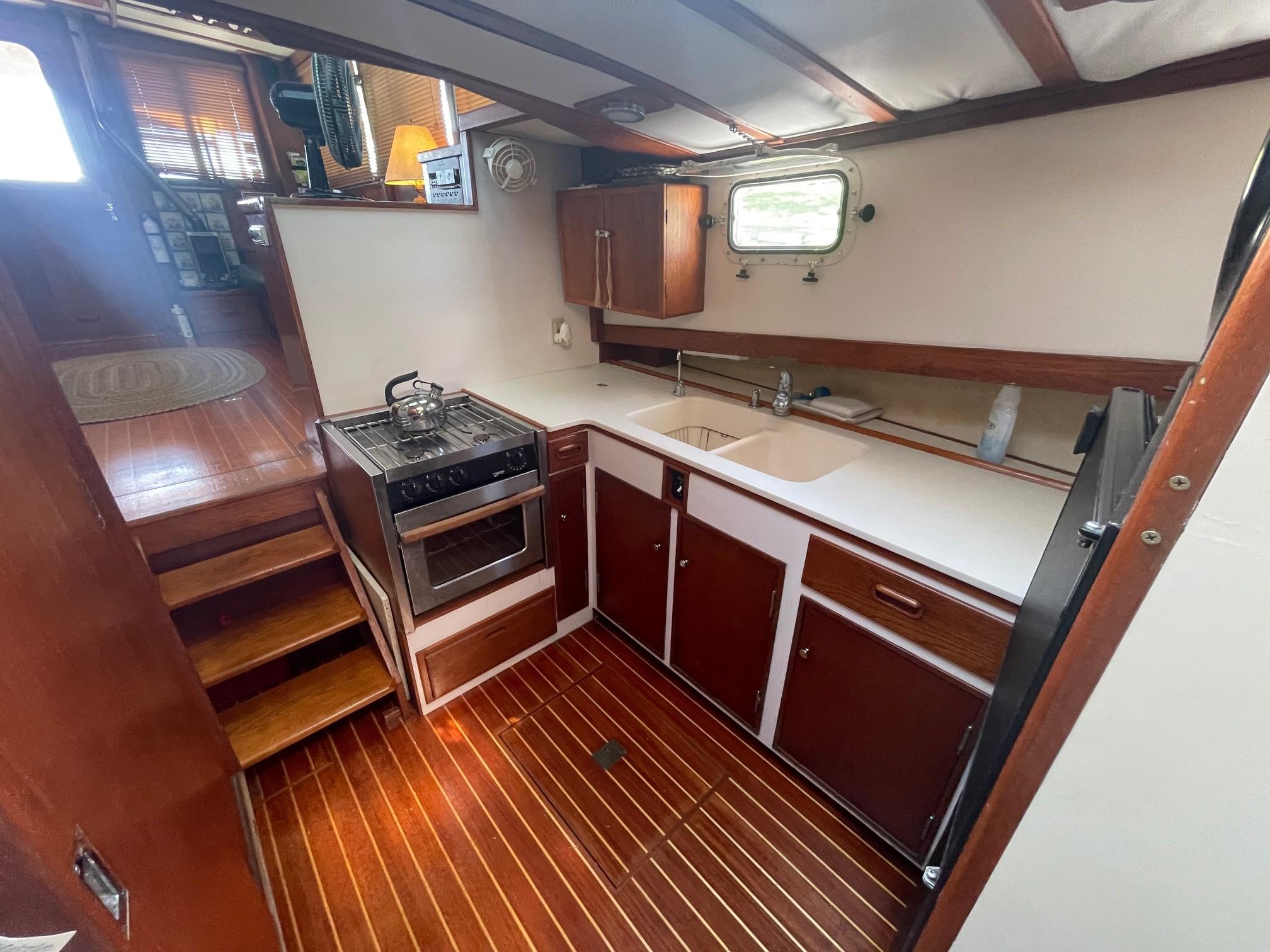 1979 Jarvis Newman Trawler kitchen with wooden cabinetry, stove, and sink.