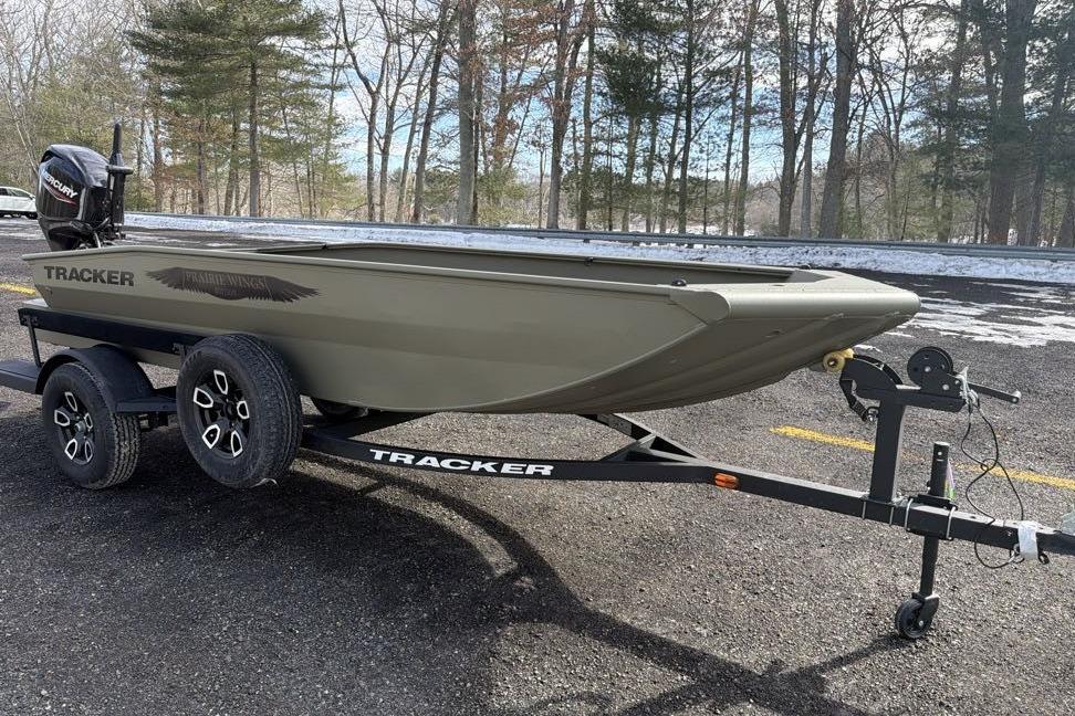 2026 Tracker Grizzly 1650 T Prairie Wings Edition boat on trailer in wooded area.