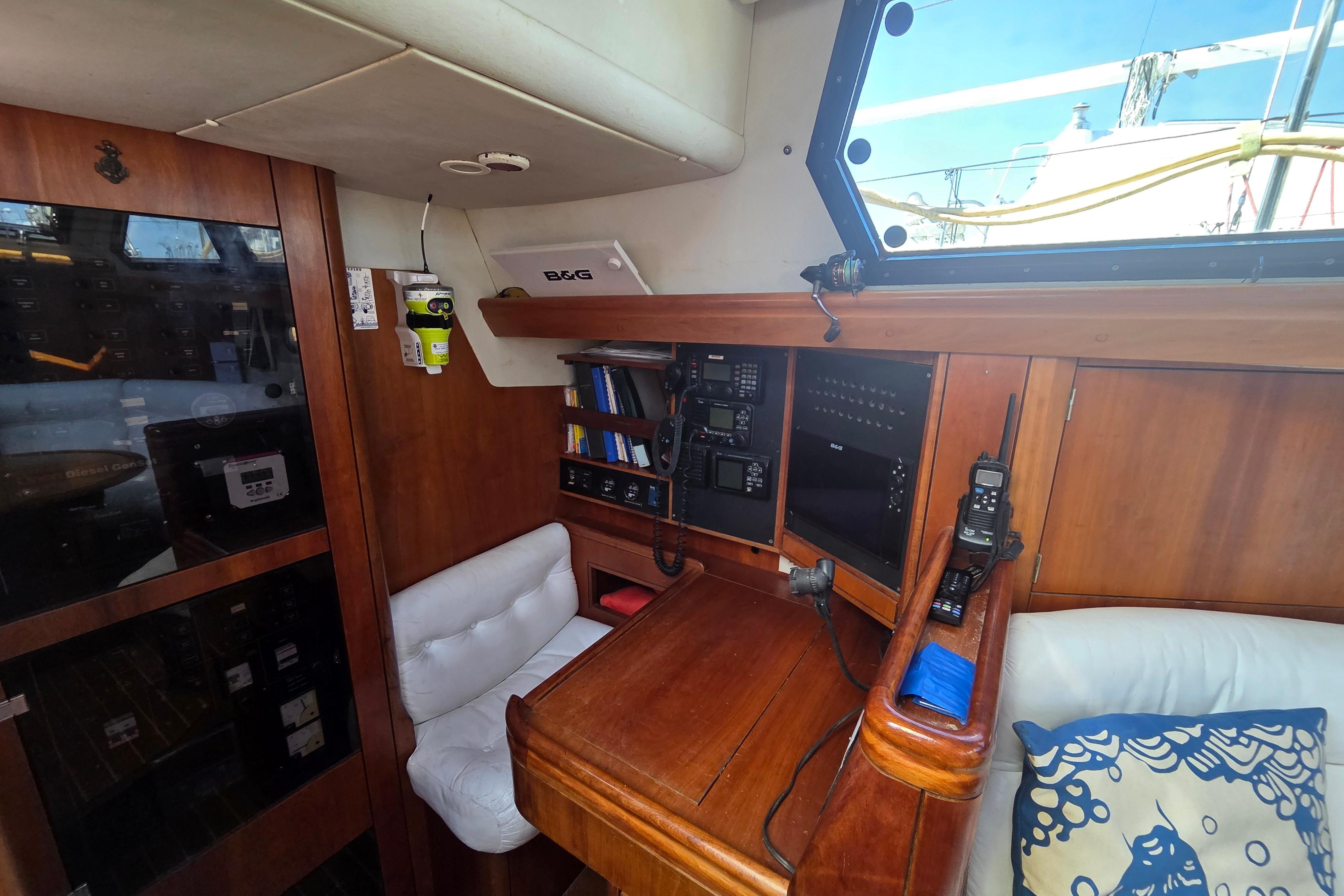Interior of 1998 Oyster 485 Deck Saloon with navigation equipment and wooden furnishings.