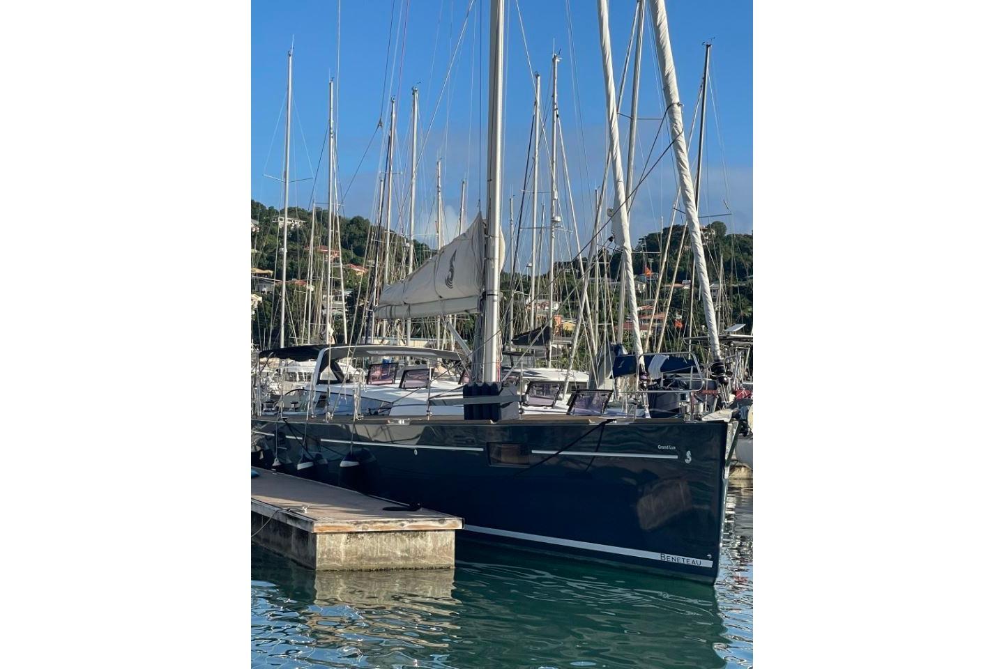 2015 Beneteau Sense 55 sailboat docked in a marina, surrounded by other yachts.