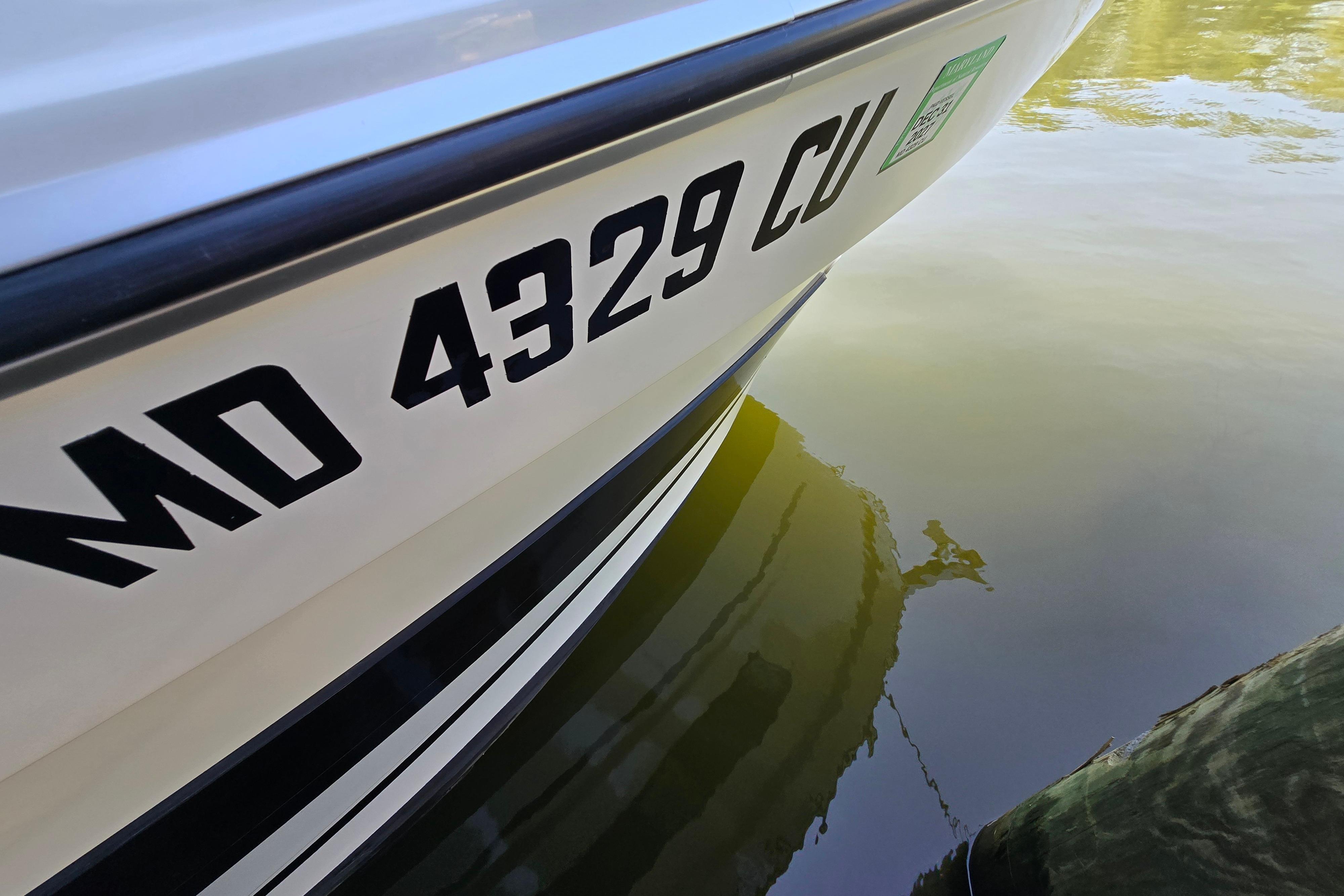Close-up of the boat hull with registration number on calm water.