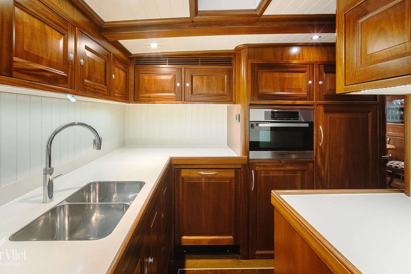 Luxurious wooden kitchen interior on a 2004 Bloemsma 100 yacht, featuring modern appliances.
