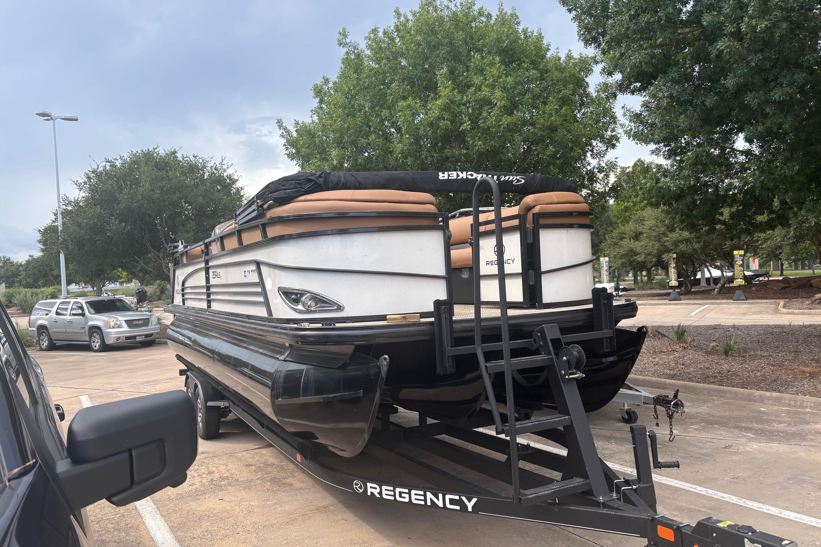 2018 Regency 254 LE3 Sport pontoon boat on trailer in parking lot.