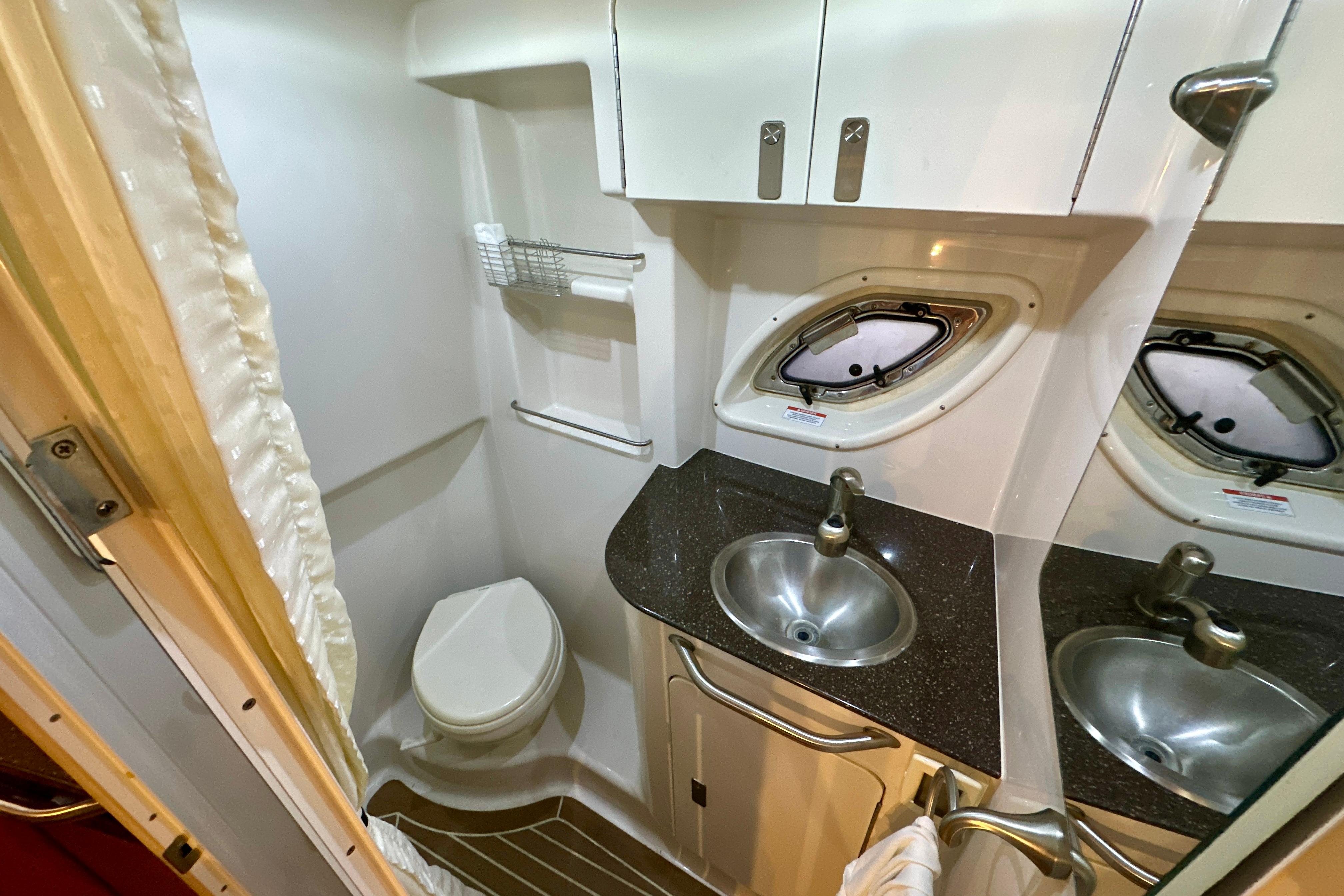 2012 Sea Ray 330 Sundancer bathroom with sink, toilet, and porthole window.