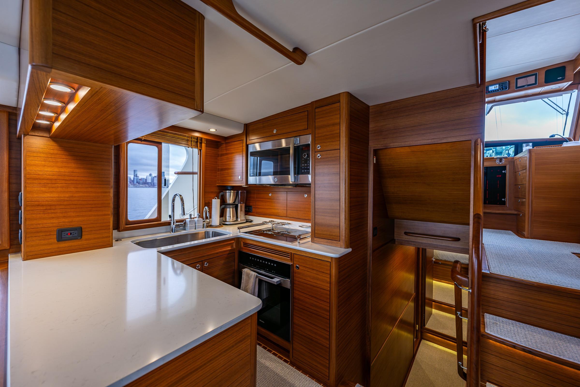 Luxurious kitchen interior of 2026 Fleming 55 Pilothouse yacht with modern appliances and wood finish.