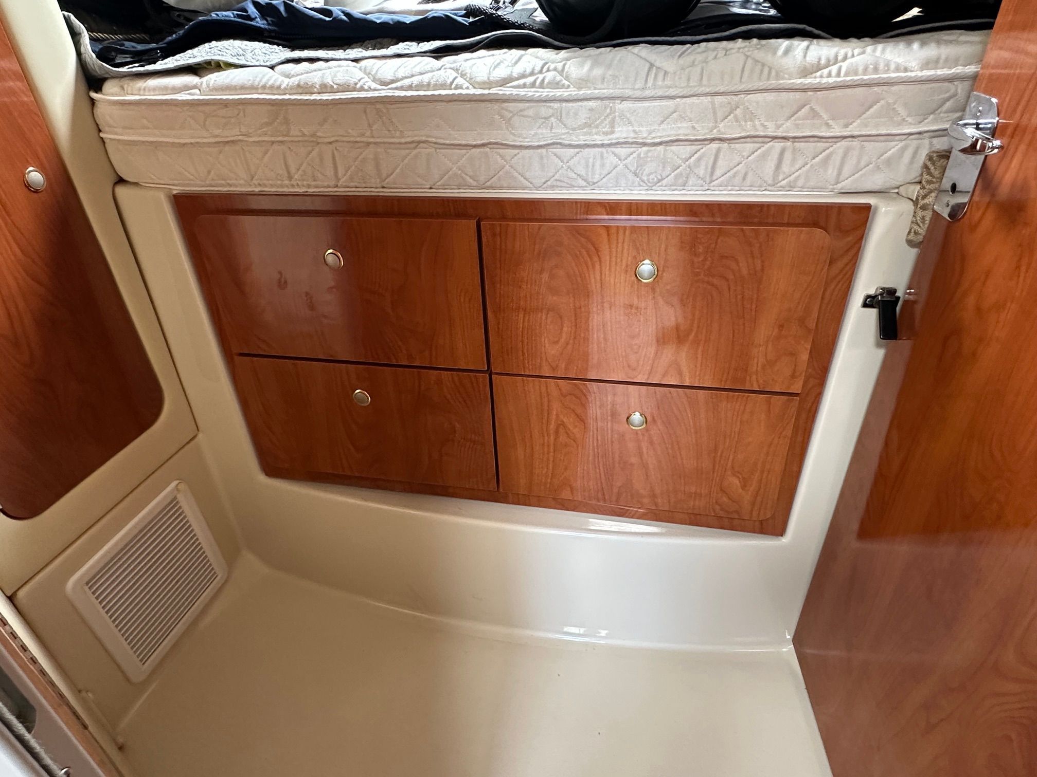 Interior of a boat with wooden cabinetry and a mattress on top.