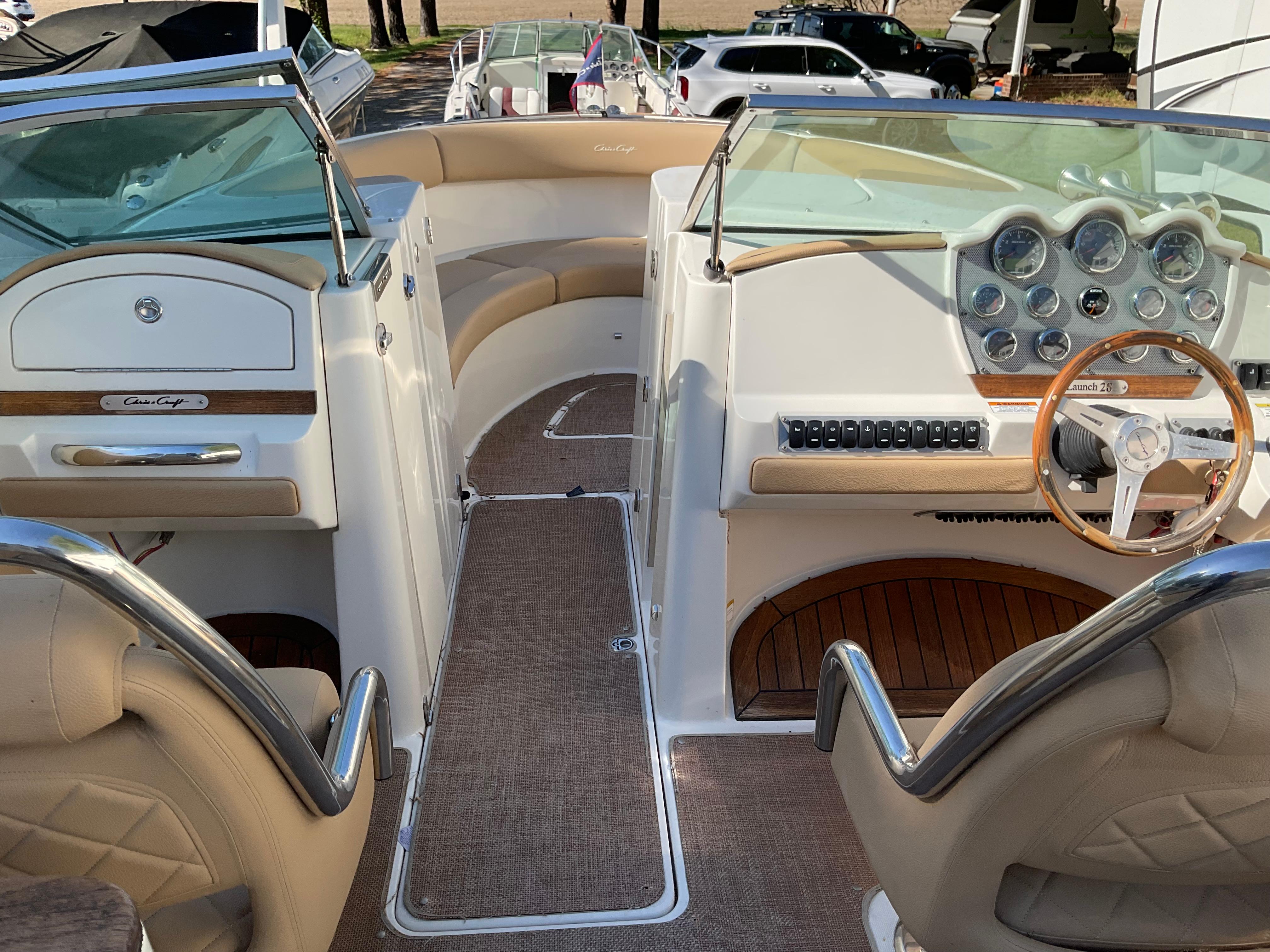 2014 Chris-Craft Launch 28 boat interior with beige seating and wooden steering wheel.